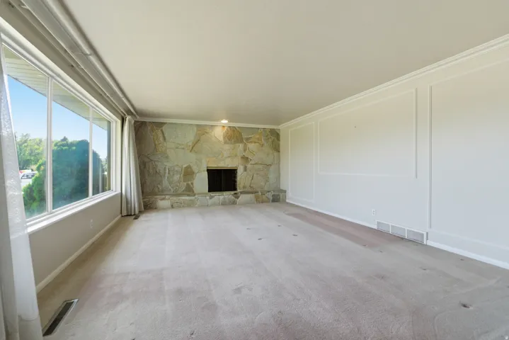 Living room featuring a full-height stone fireplace with a black firebox, expansive windows, and paneled wall detailing