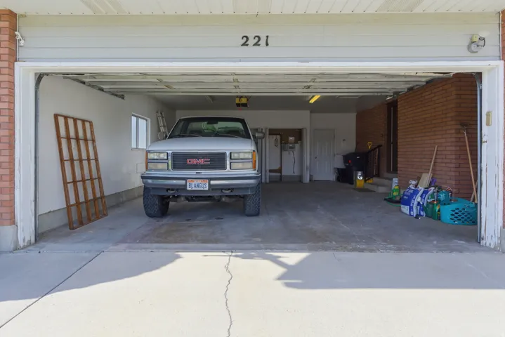 Two-car garage with overhead door, concrete flooring, and brick wall accents