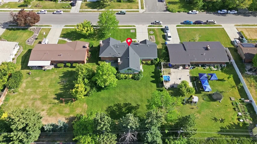 Expansive property featuring a large, manicured lawn with mature trees, paved patio area, and a dark shingle roof