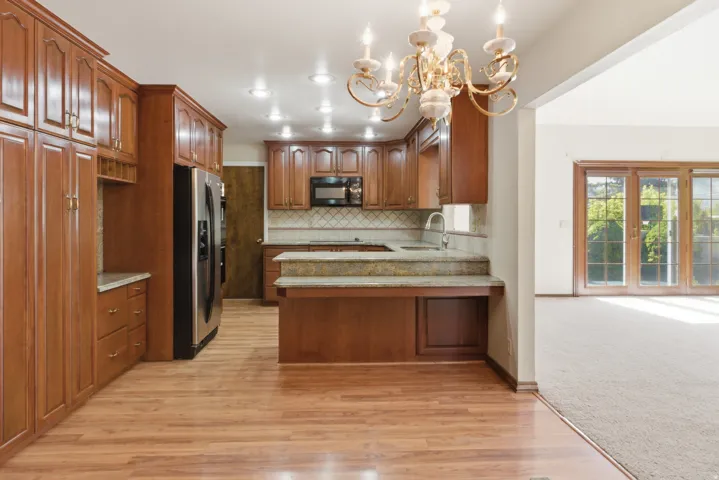 Kitchen featuring wood-finish flooring and extensive cabinetry with gold-tone hardware