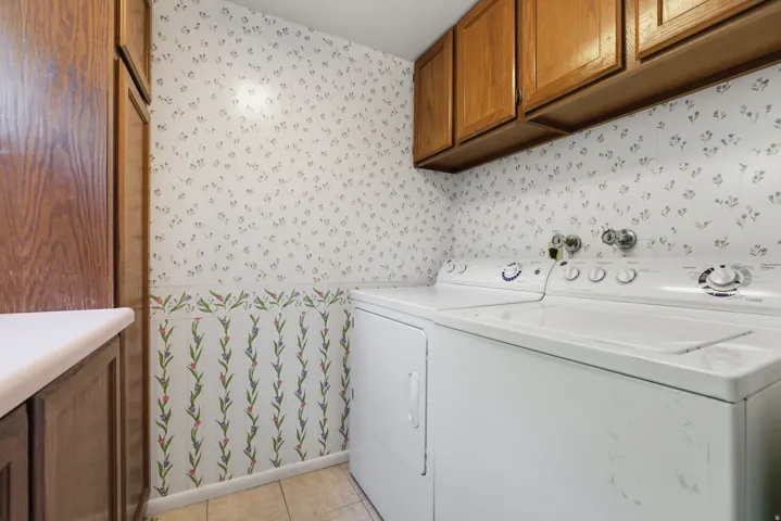 Laundry room featuring a full-size washer and dryer, wood-finish cabinetry, built-in storage, and tile flooring