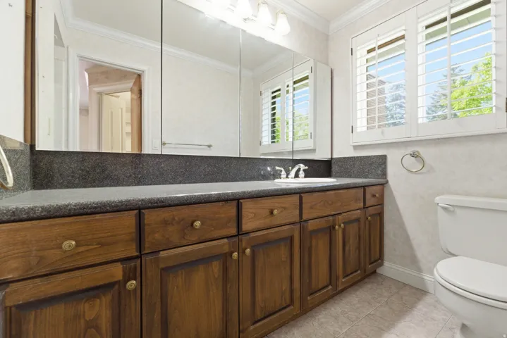 Bathroom vanity featuring wood cabinetry, a dark countertop, and an integrated sink