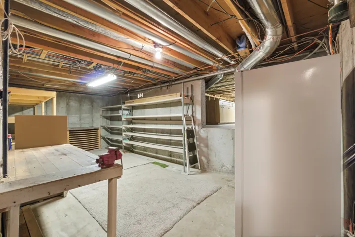 Unfinished basement featuring concrete walls and exposed ceiling joists