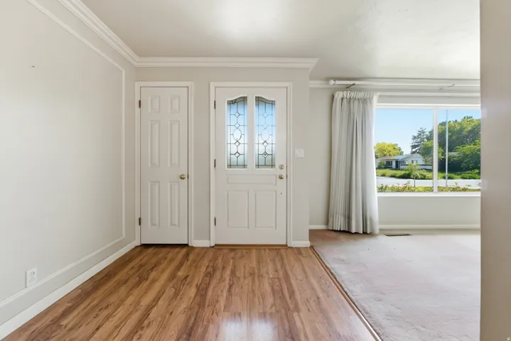 Entryway featuring wood-finish flooring, a white six-panel door, and a white front door with decorative leaded glass