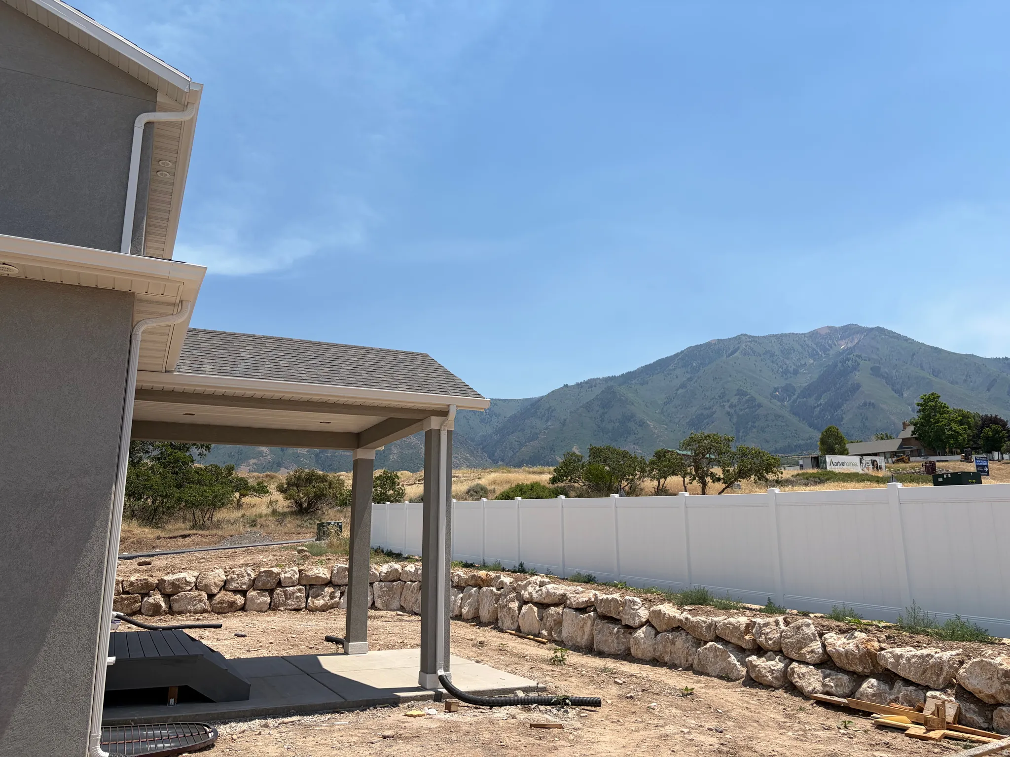 Covered patio area with concrete slab, wood-finish decking, and stone retaining wall
