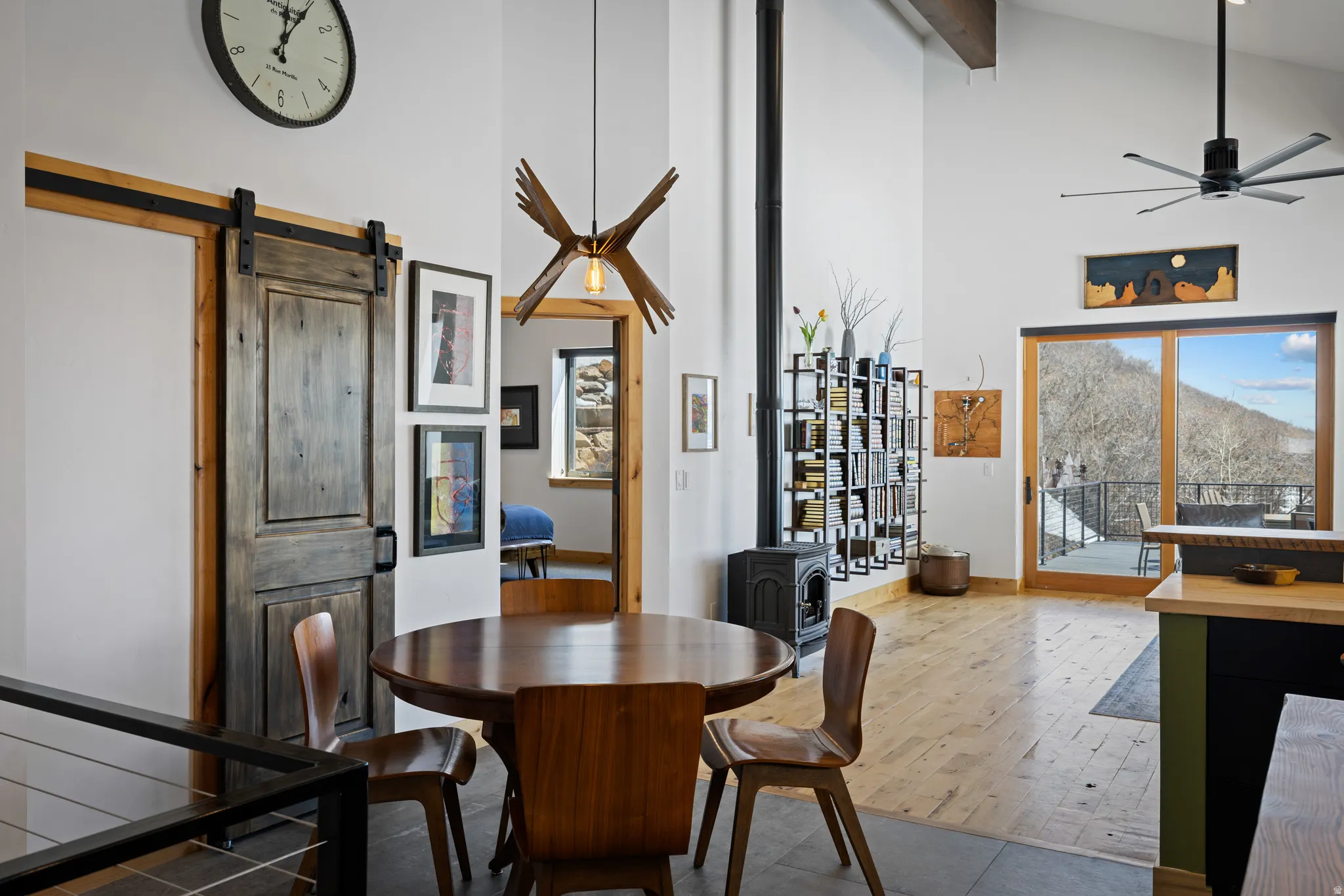 Dining space featuring a wood stove, a mountain view, a ceiling fan, a barn door, and vaulted ceiling