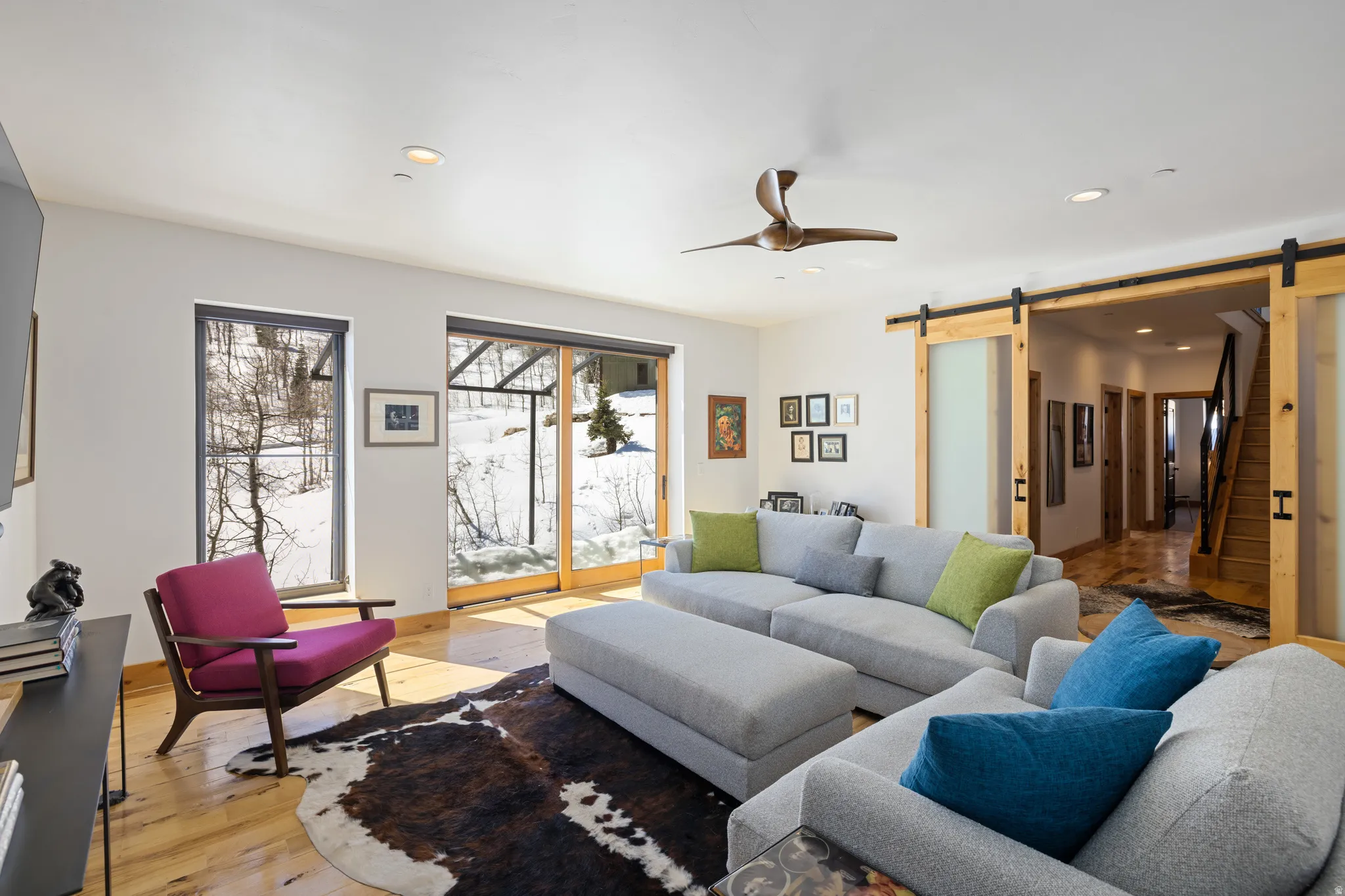 Living room featuring wood-type flooring, a barn door, recessed lighting, and a ceiling fan