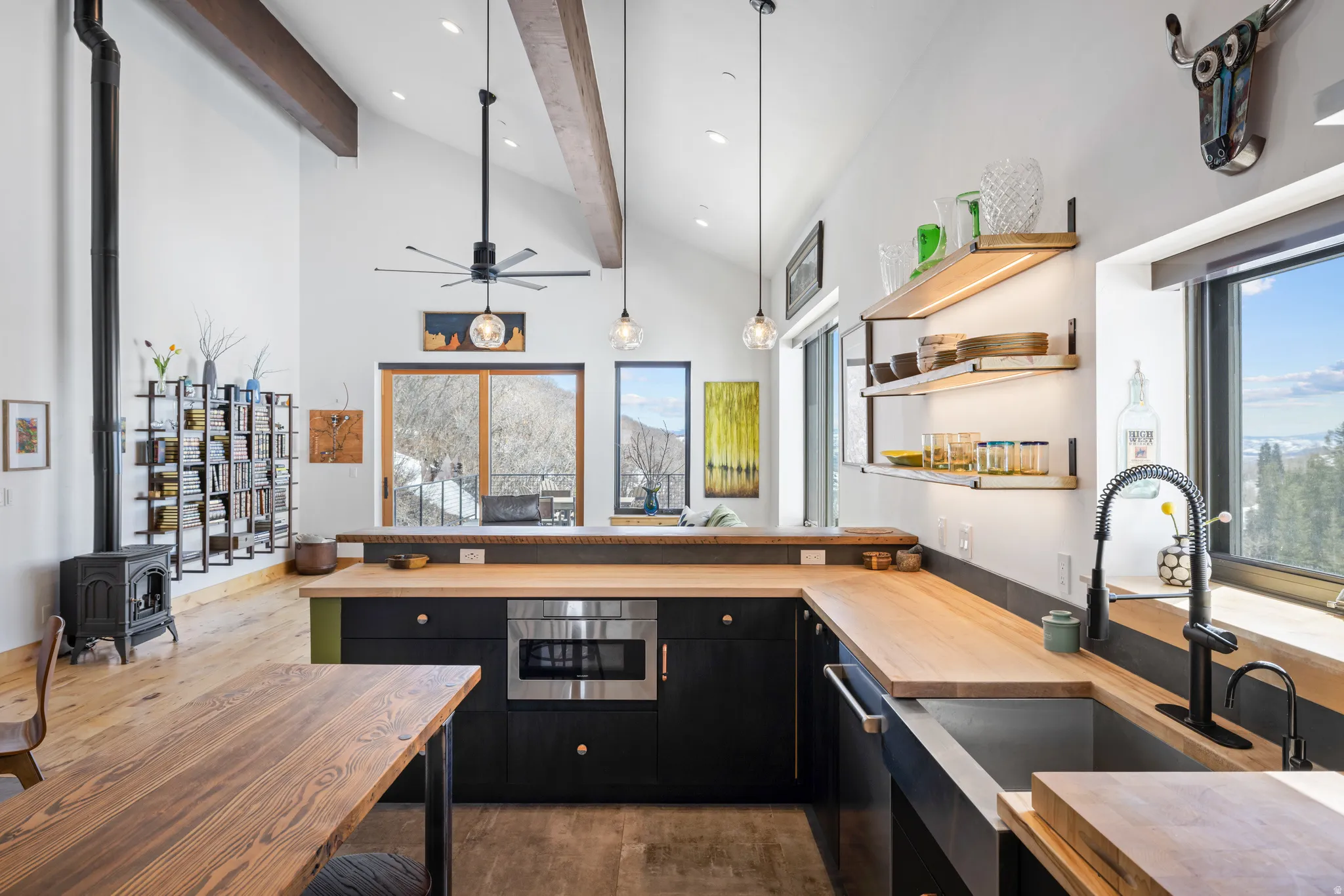 Kitchen with dark cabinets, wooden counters, open shelves, light wood-style flooring, and a peninsula