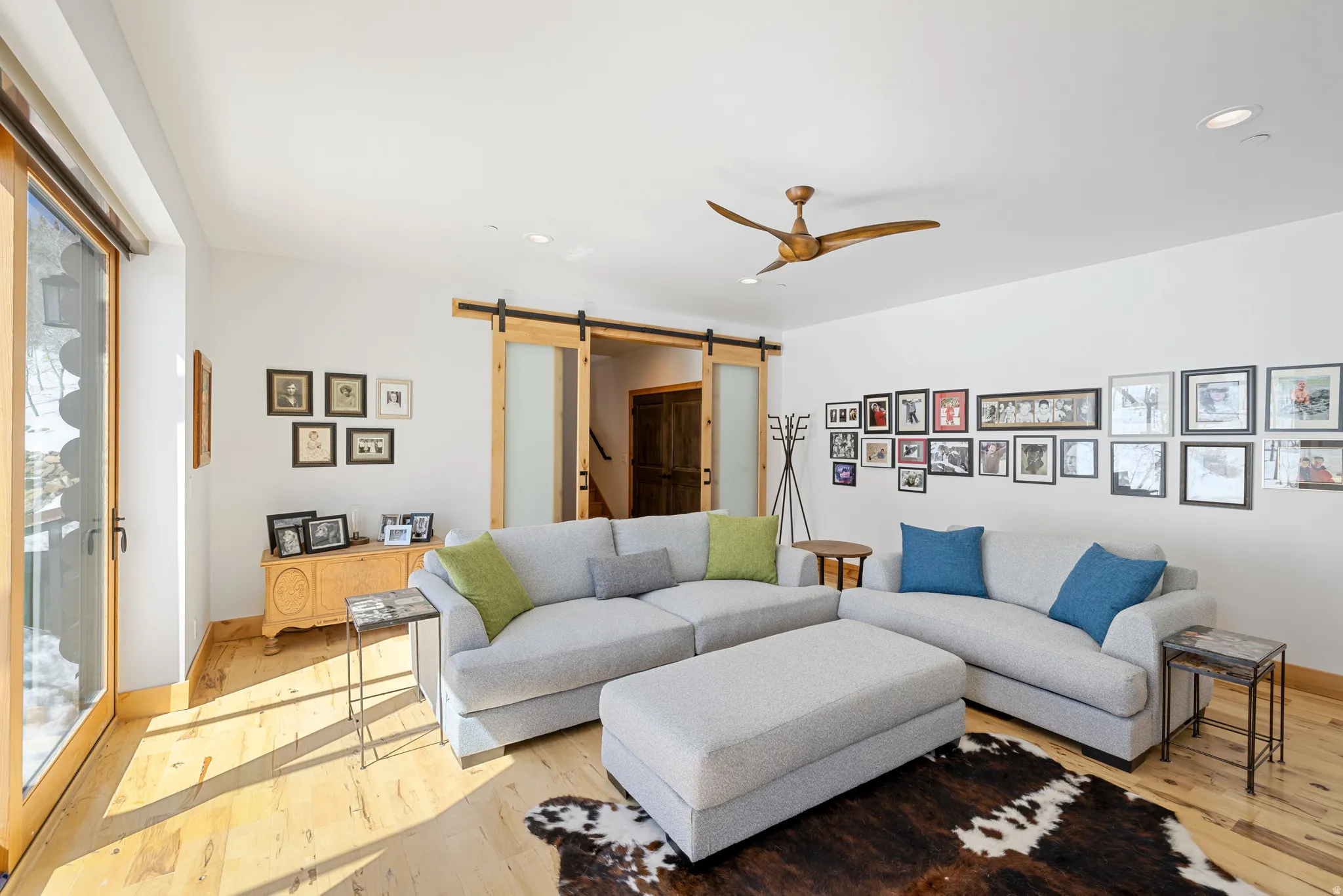 Living area featuring a barn door, ceiling fan, light wood finished floors, and recessed lighting