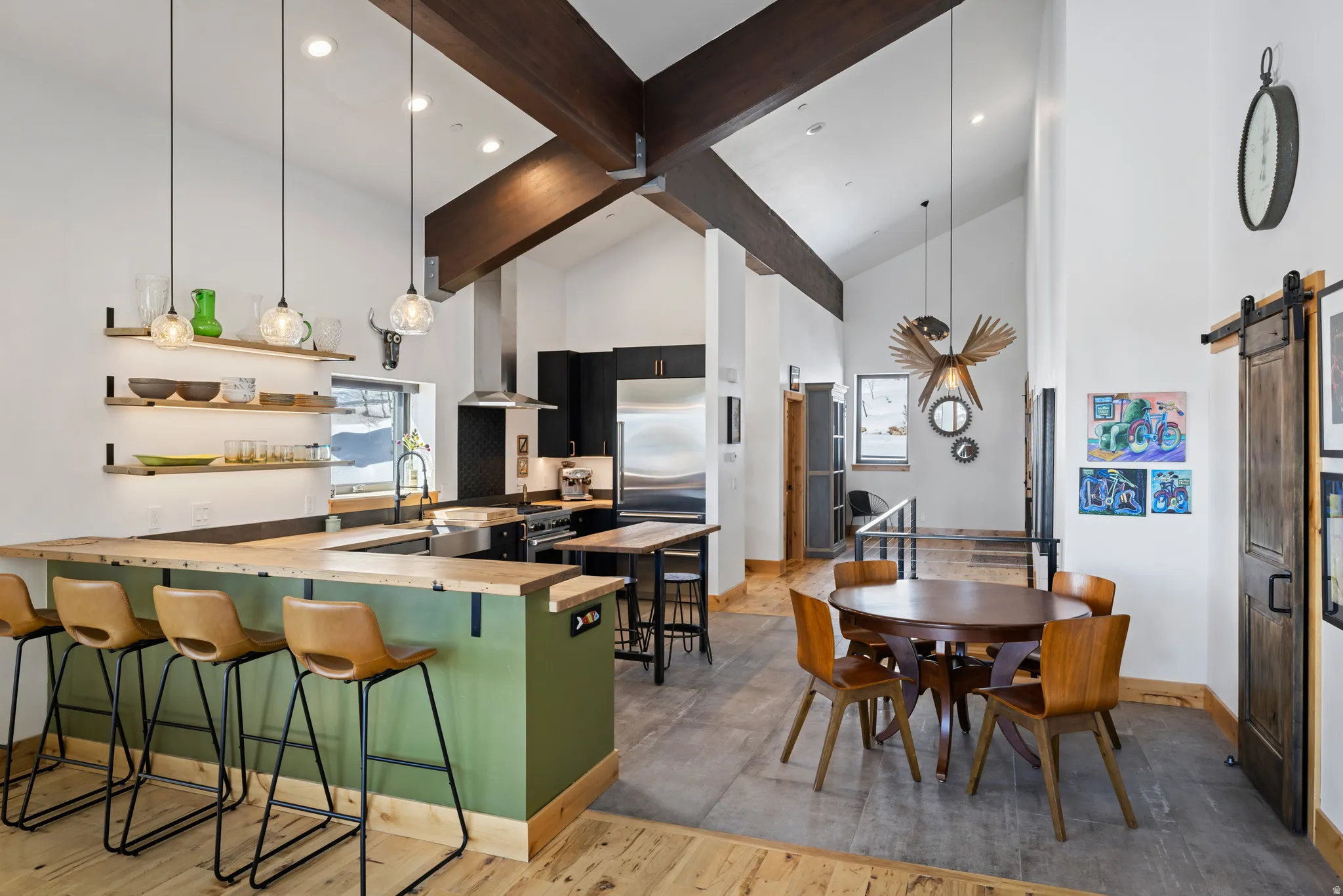 Kitchen with a barn door, a breakfast bar area, a peninsula, light wood-style flooring, and dark cabinetry