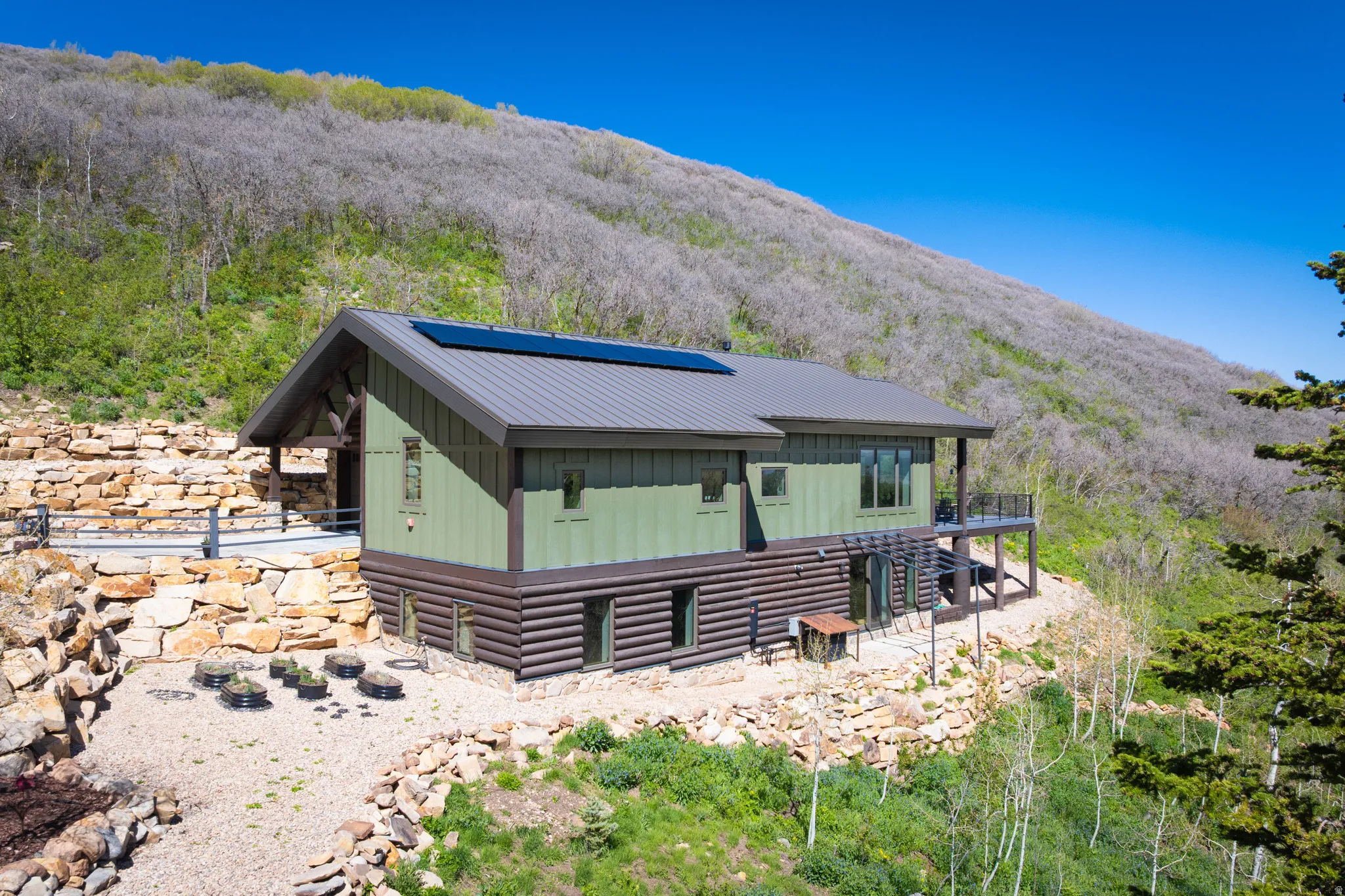 View of front of property with a metal roof, a mountain view, solar panels, and log exterior