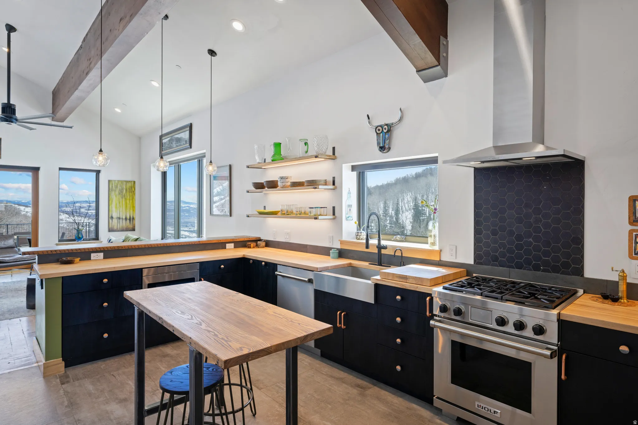 Kitchen with dark cabinetry, stainless steel appliances, a peninsula, wood counters, and open shelves
