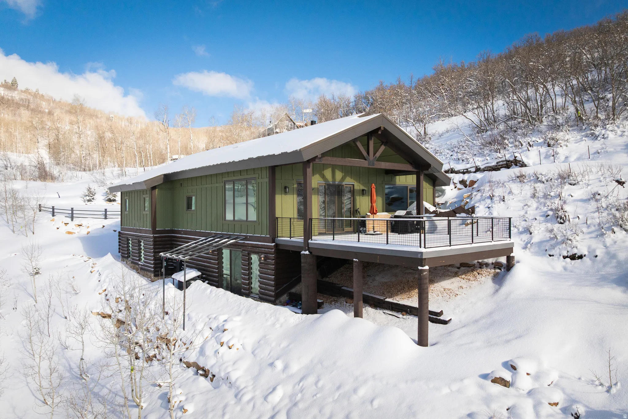 Snow covered back of property with a wooden deck
