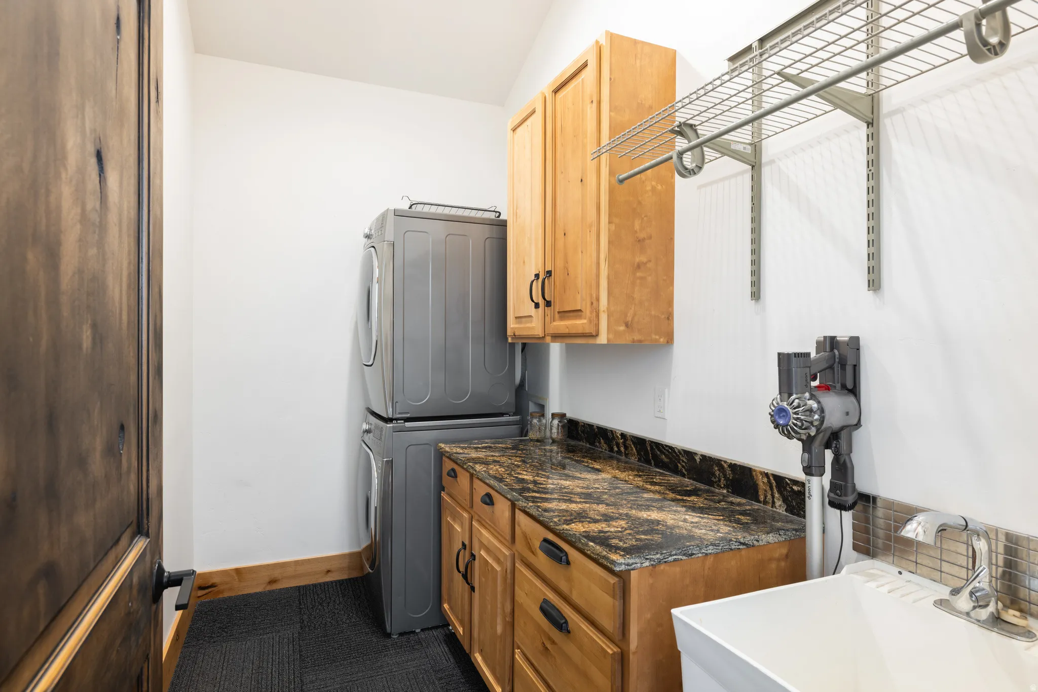 Laundry room featuring stacked washer and dryer and cabinet space