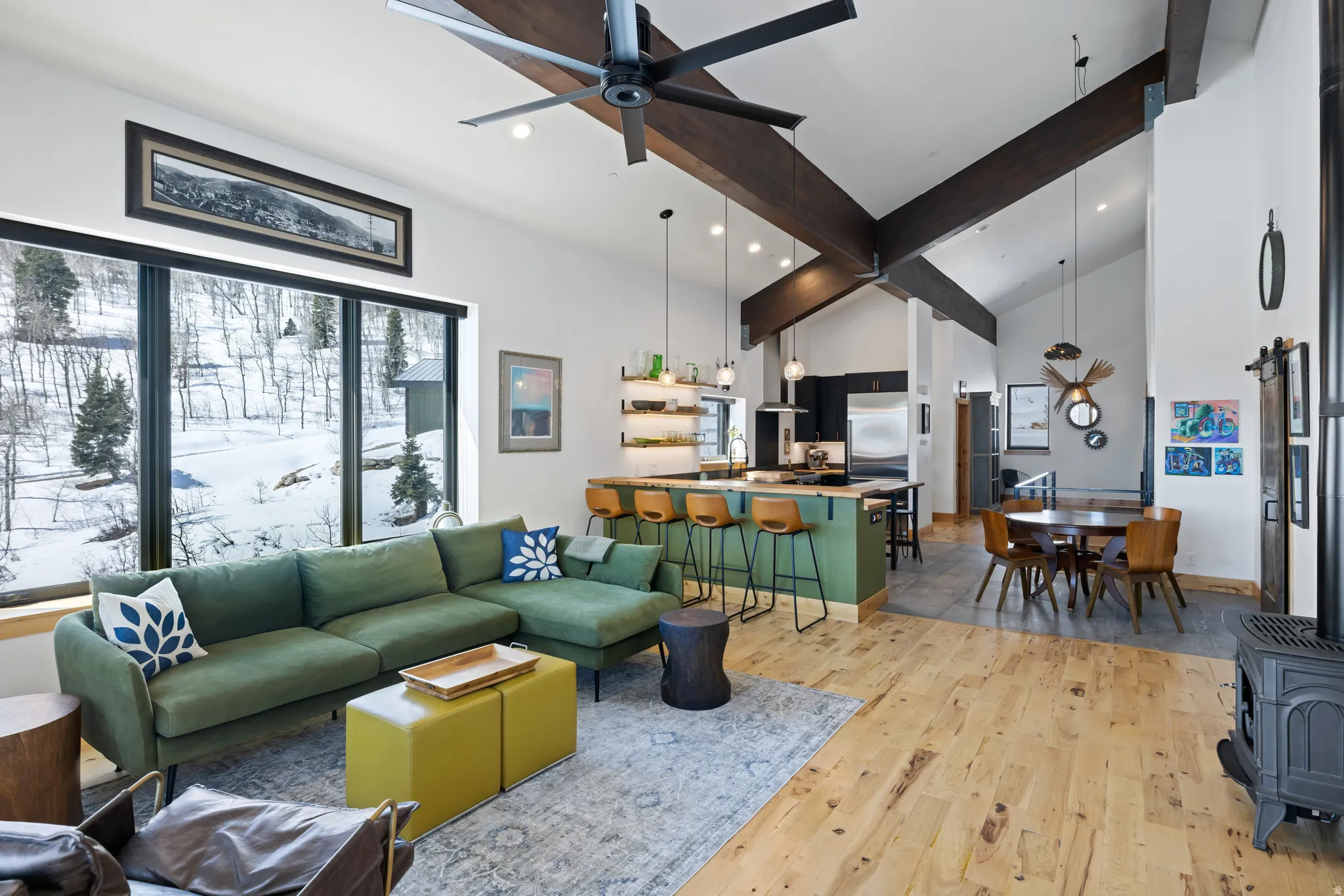 Living room with a wood stove, light wood finished floors, a ceiling fan, vaulted ceiling, and recessed lighting