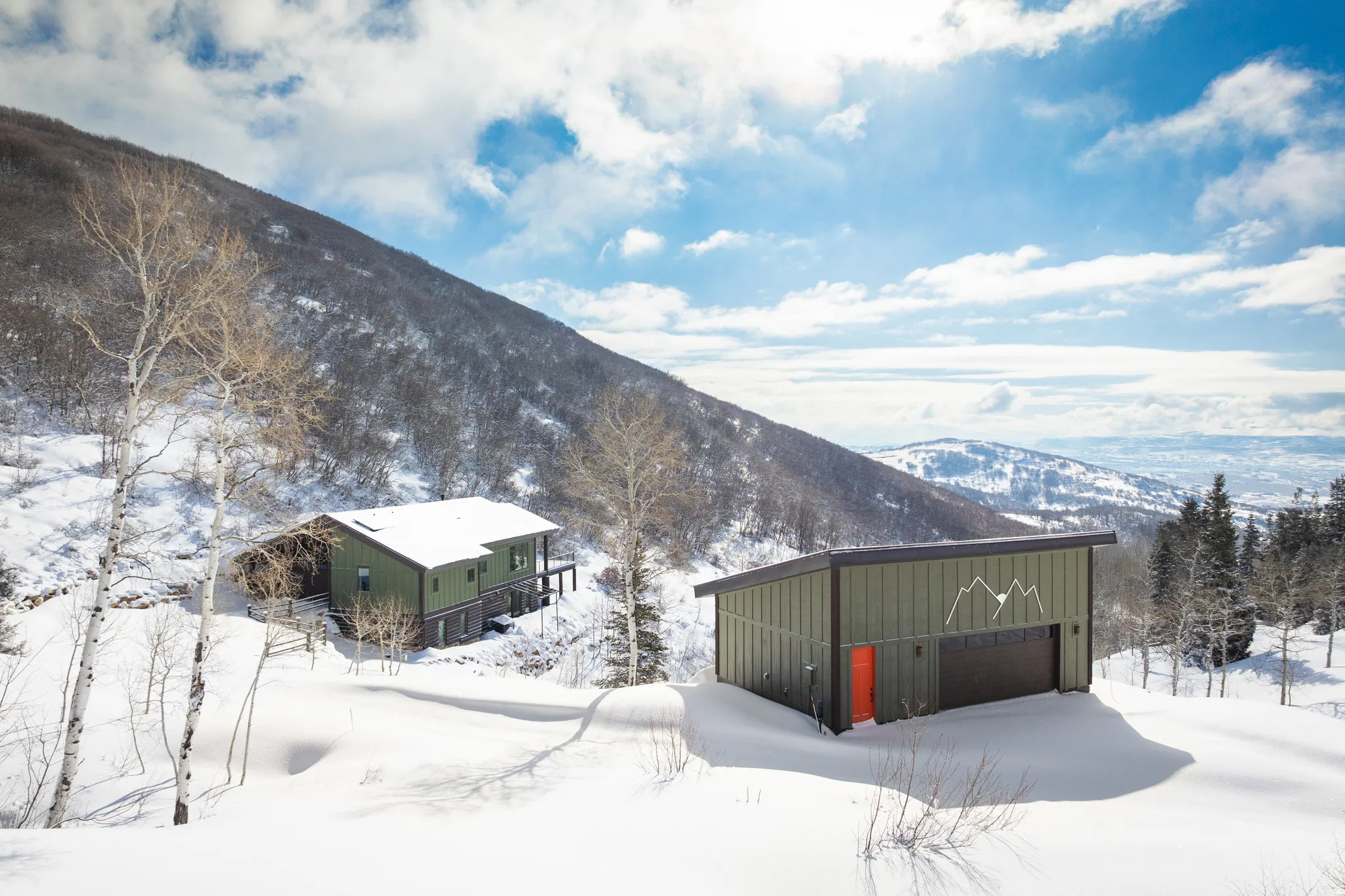 View of snowy exterior featuring an outbuilding, a mountain view, and board and batten siding