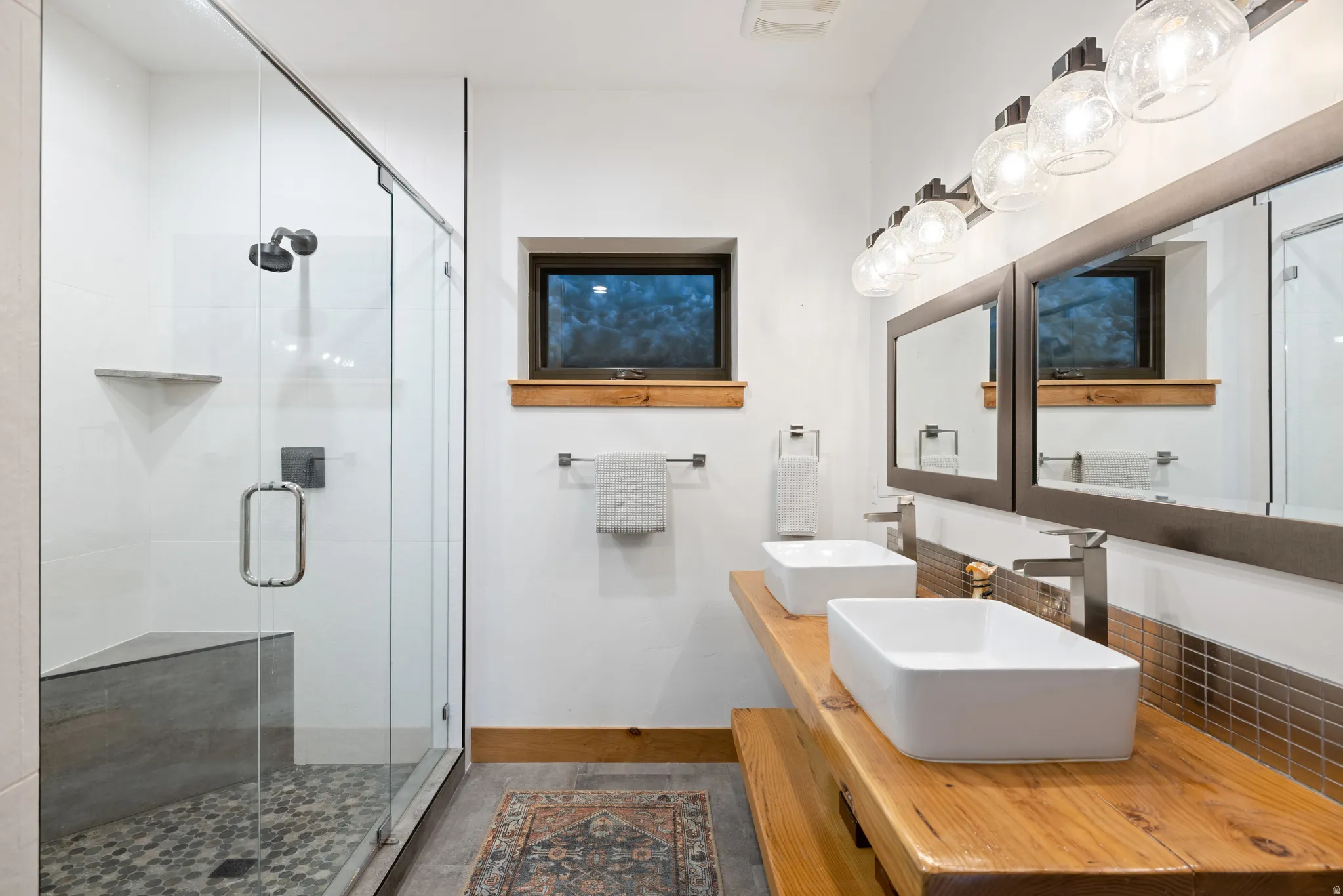 Full bath featuring a shower stall and double vanity