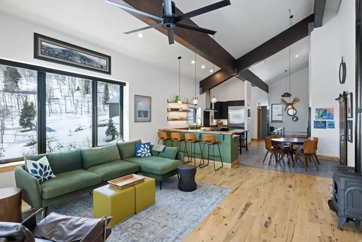 Living room with a wood stove, light wood finished floors, a ceiling fan, vaulted ceiling, and recessed lighting