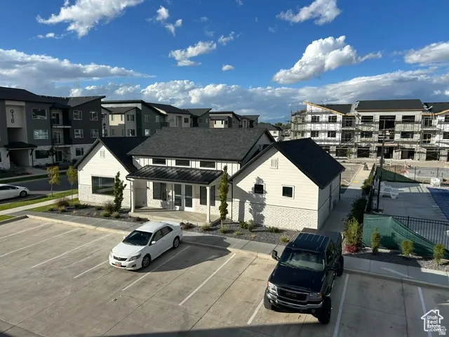 Modern architectural style with a covered entry, dark shingle roofing, and light-colored siding