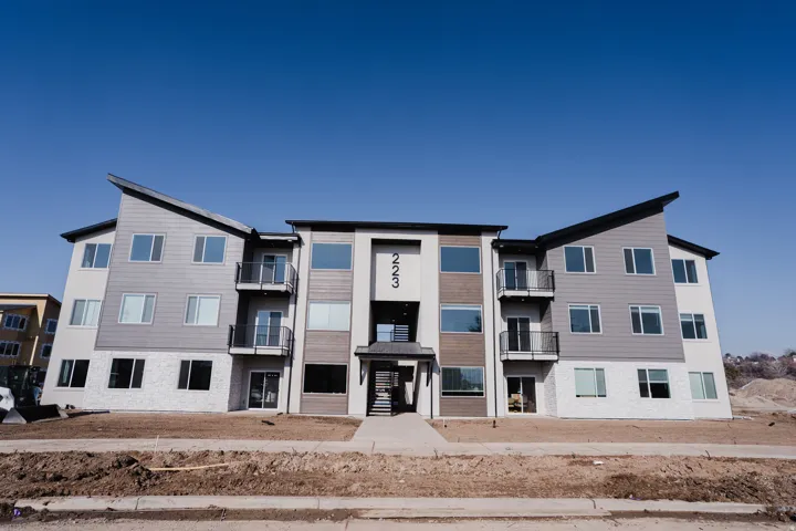Contemporary multi-story building featuring a facade of gray siding, white brick, and wood-finish accents