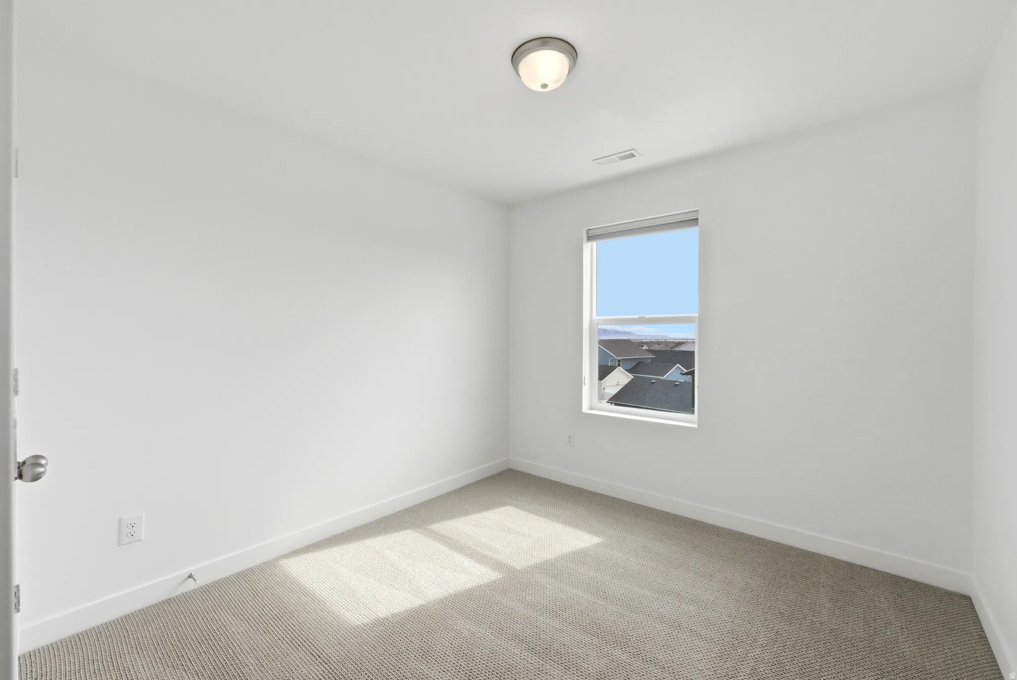 Spare room with light carpet and baseboards