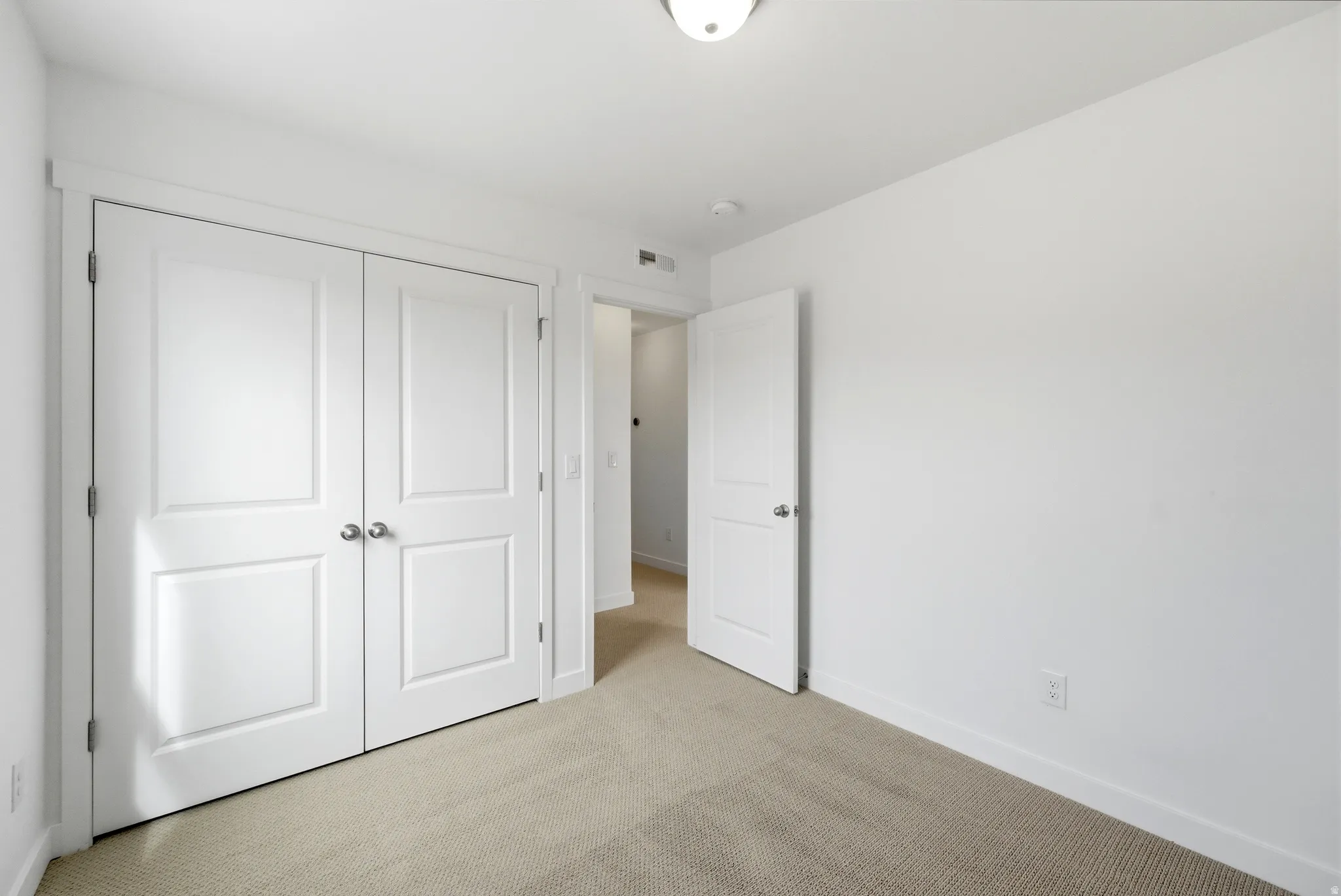 Unfurnished bedroom with light carpet and a closet