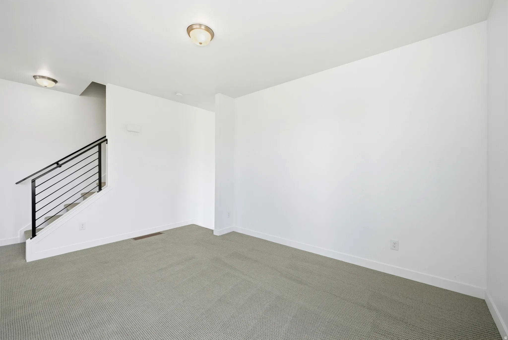 Spare room featuring dark carpet and baseboards