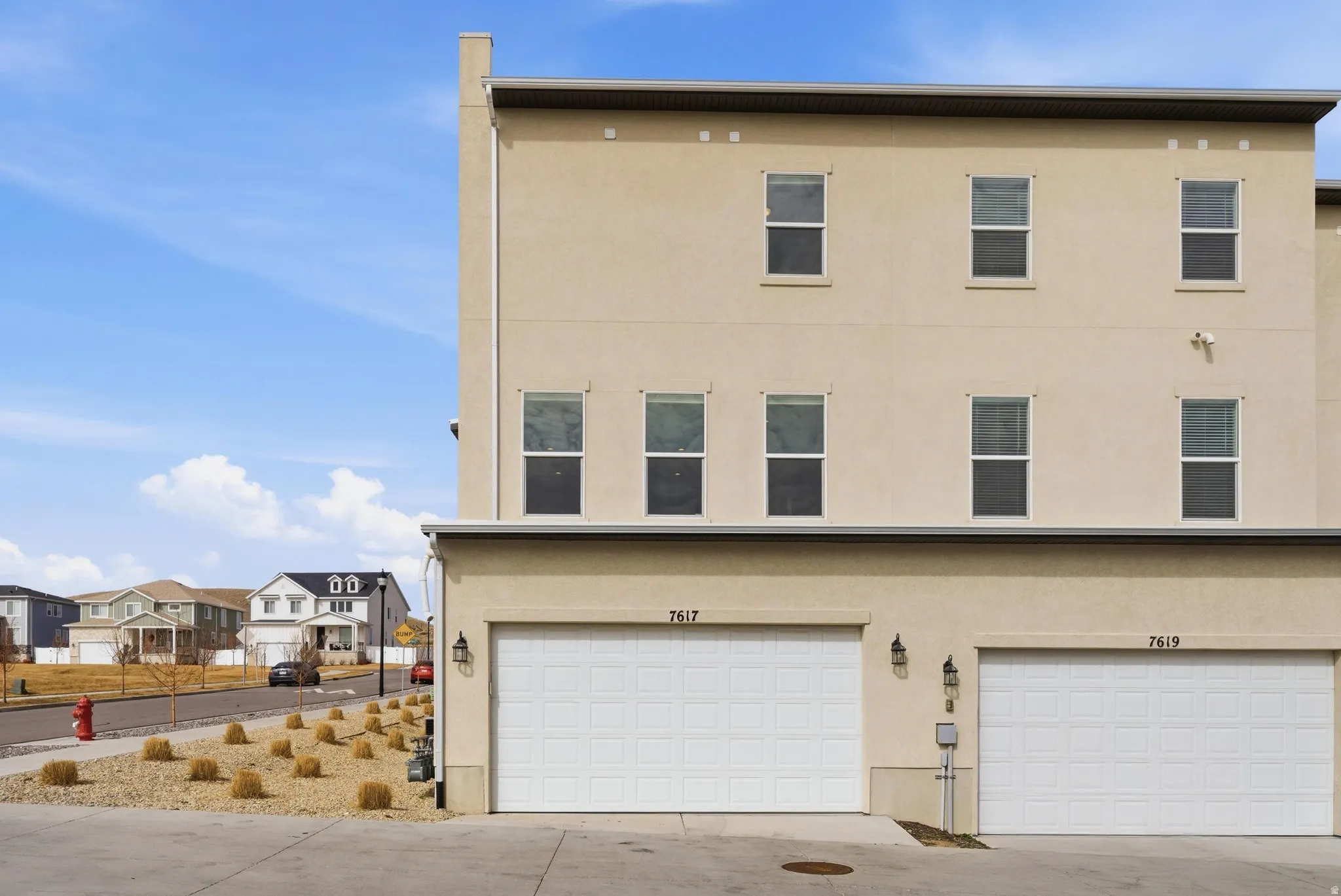 View of front facade with stucco siding, concrete driveway, an attached garage, and a residential view