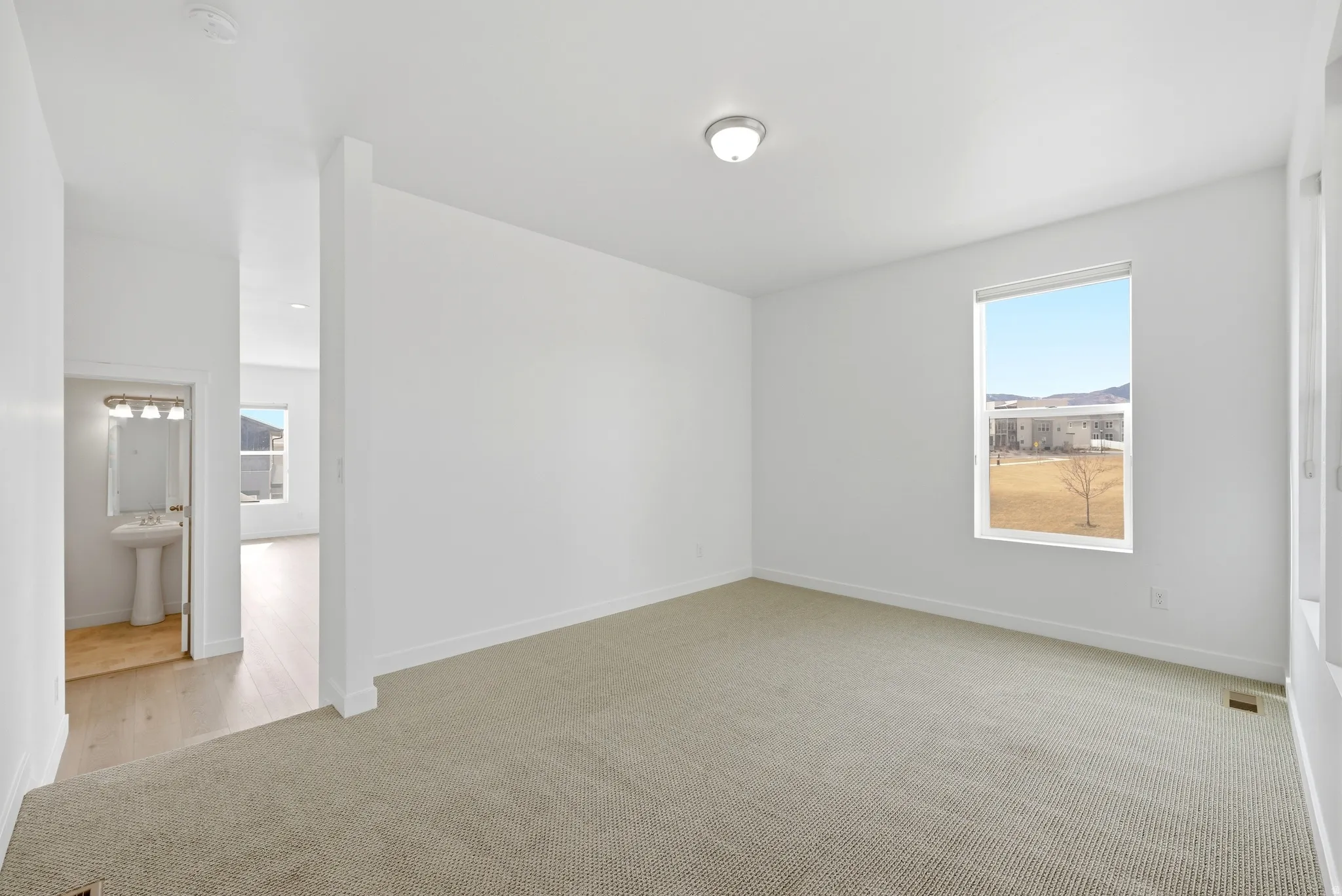 Empty room featuring light colored carpet and plenty of natural light