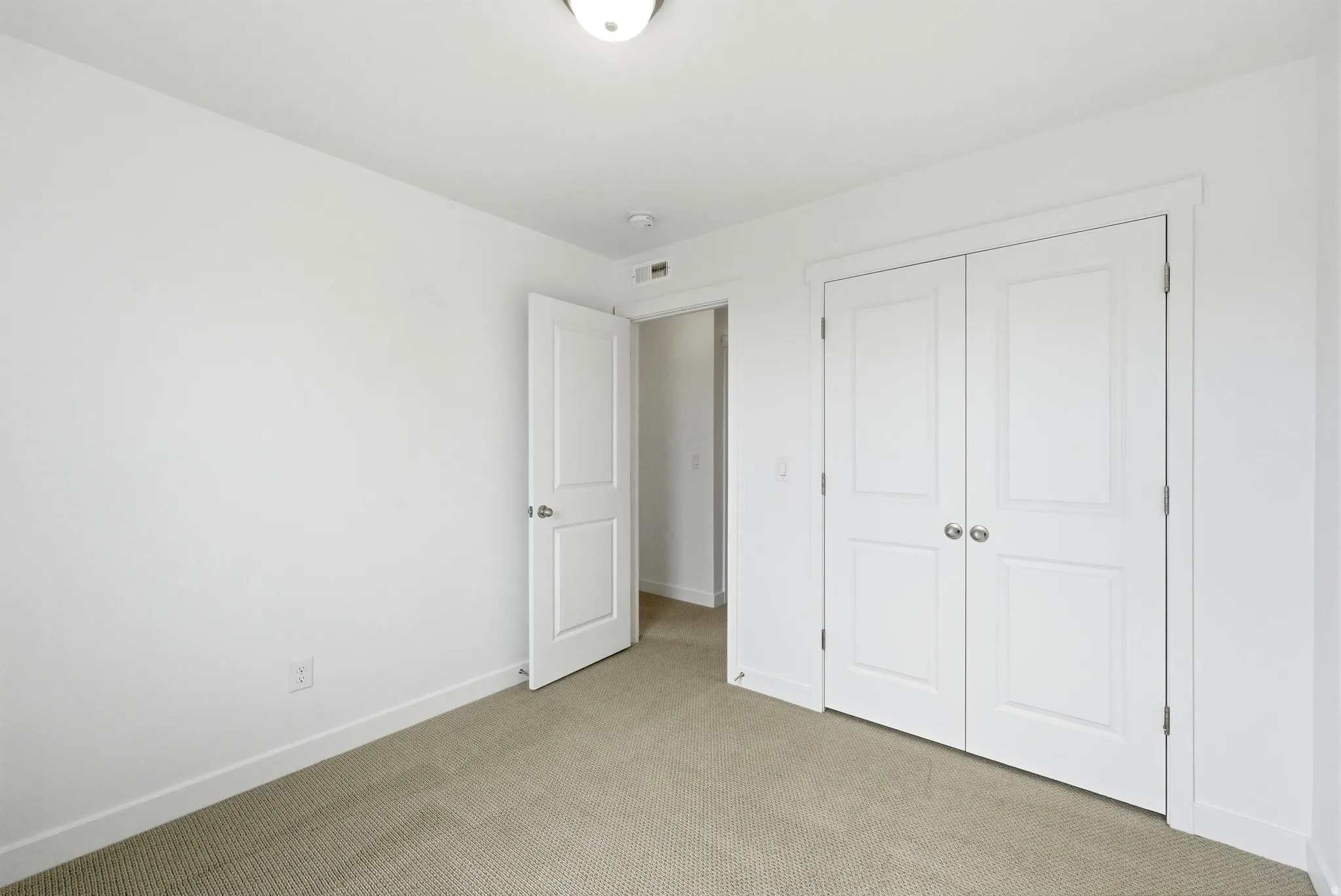 Unfurnished bedroom featuring light carpet and a closet