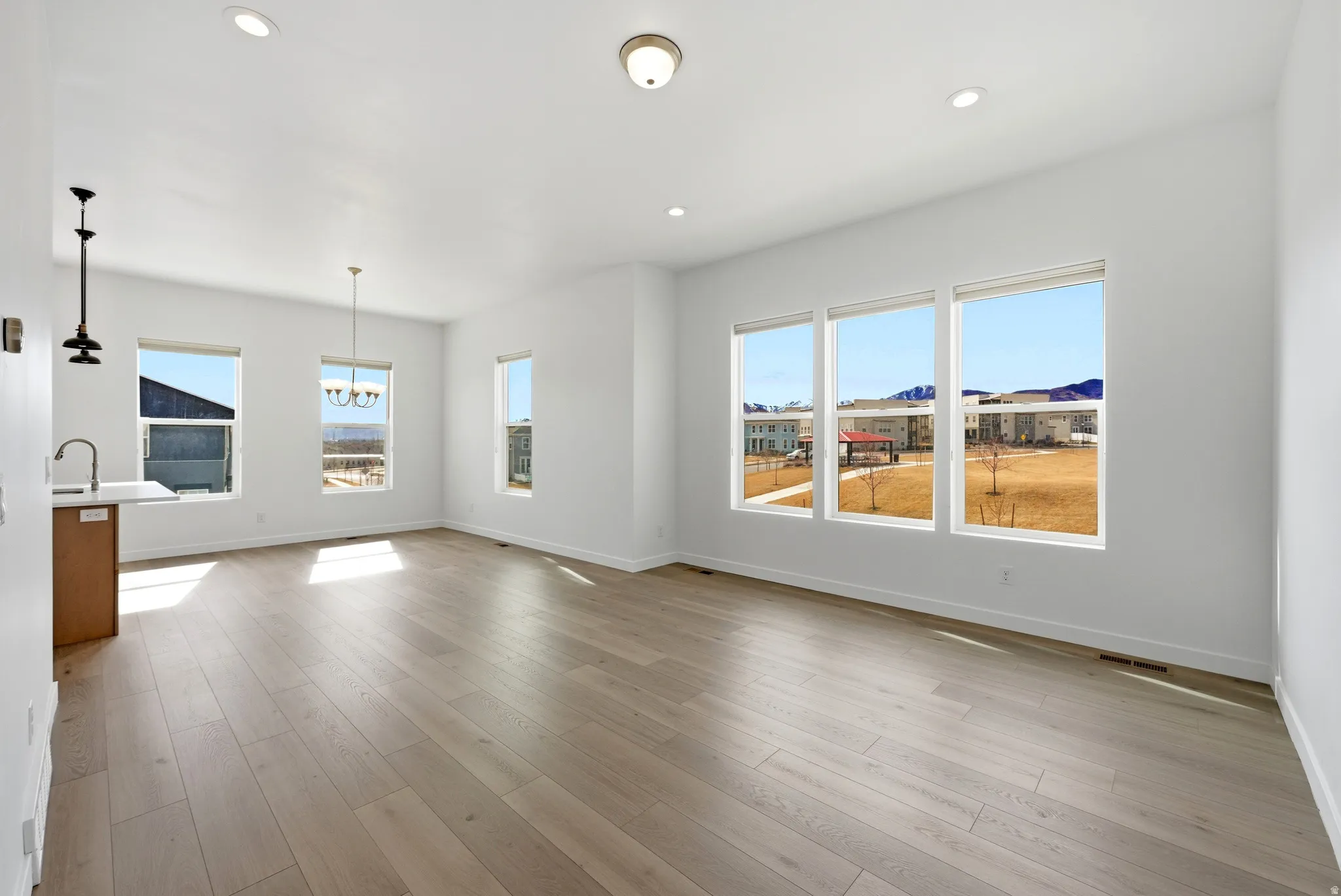 Unfurnished living room with hanging lights and light wood-style flooring