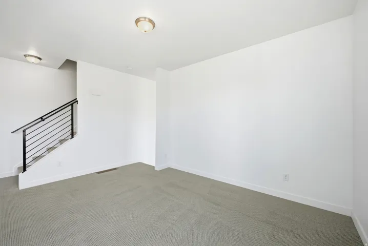 Spare room featuring dark carpet and baseboards