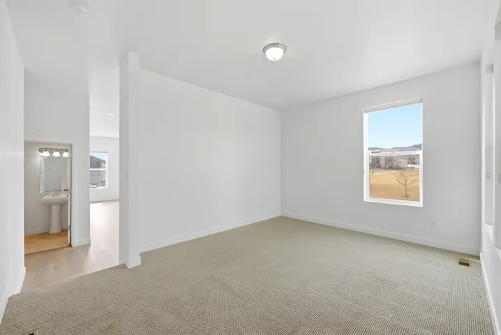 Empty room featuring light colored carpet and plenty of natural light