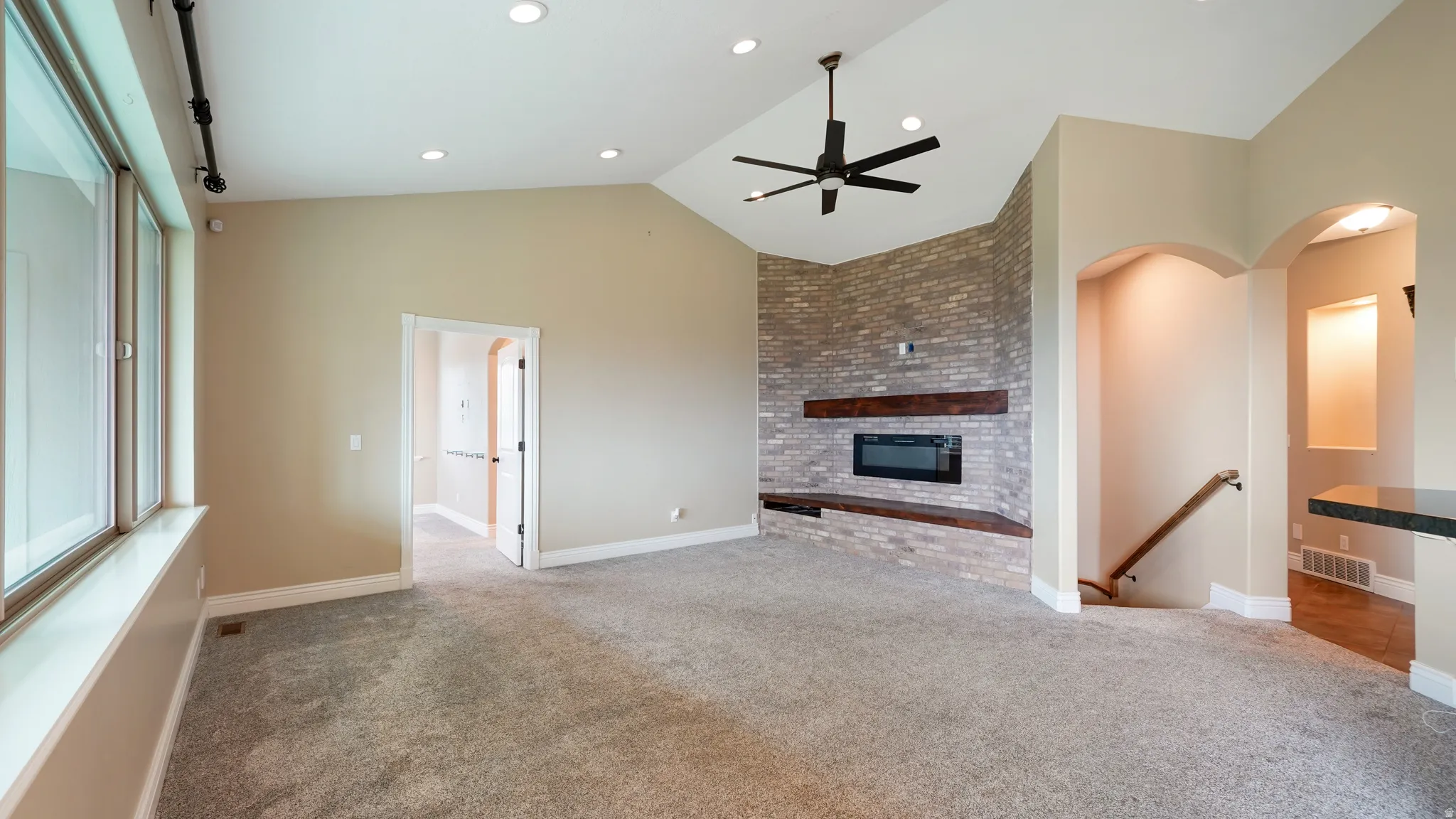 Vaulted ceiling living area featuring a modern electric fireplace with a stacked stone facade and wood-finish mantels