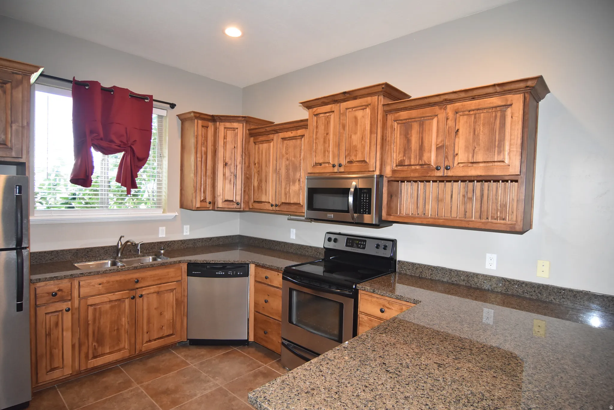 Full Kitchen featuring wood cabinetry, stainless steel appliances, granite-style countertops, and tile flooring