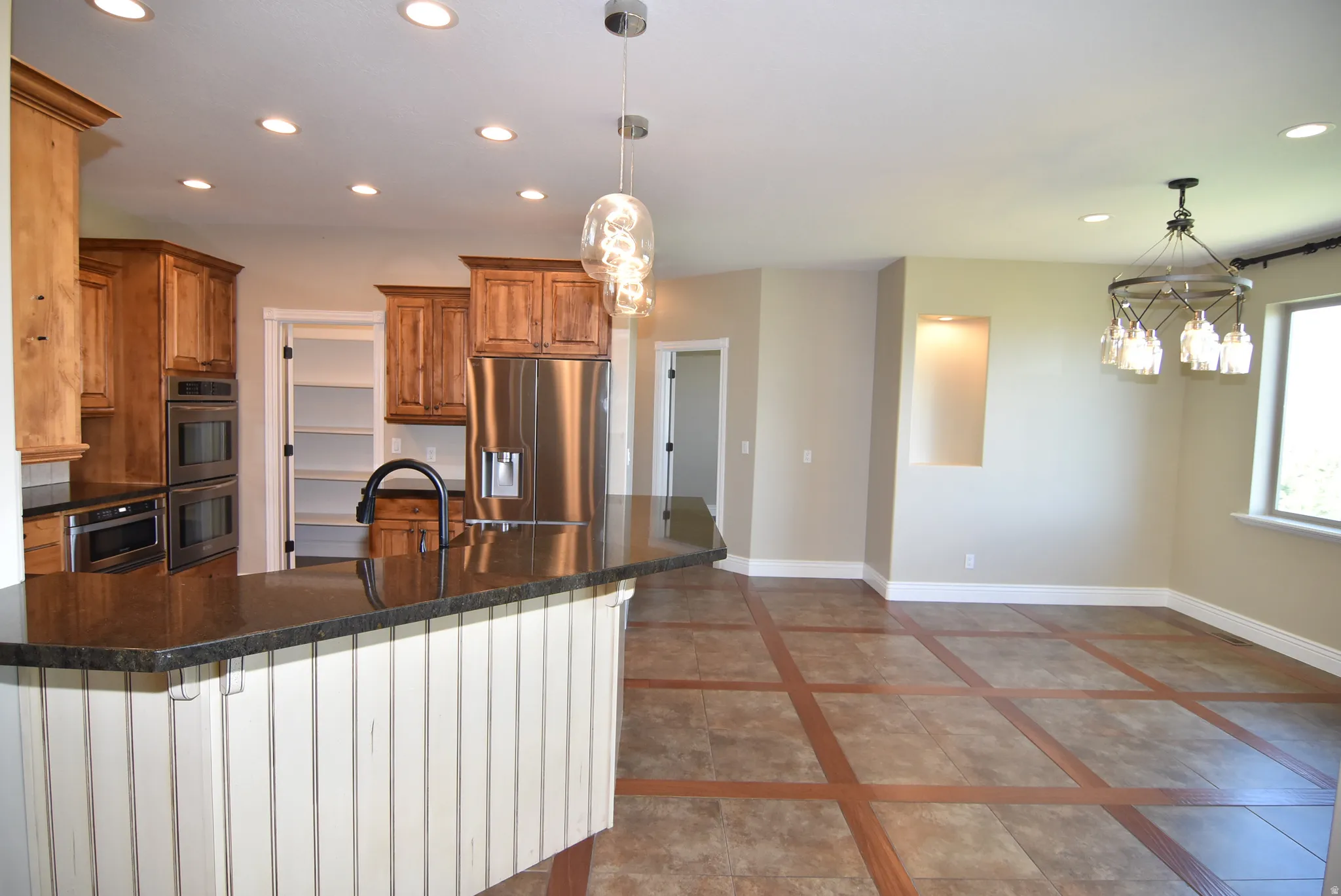 Dining area adjacent to kitchen featuring a granite-topped island with beadboard paneling, stainless steel appliances, and recessed lighting