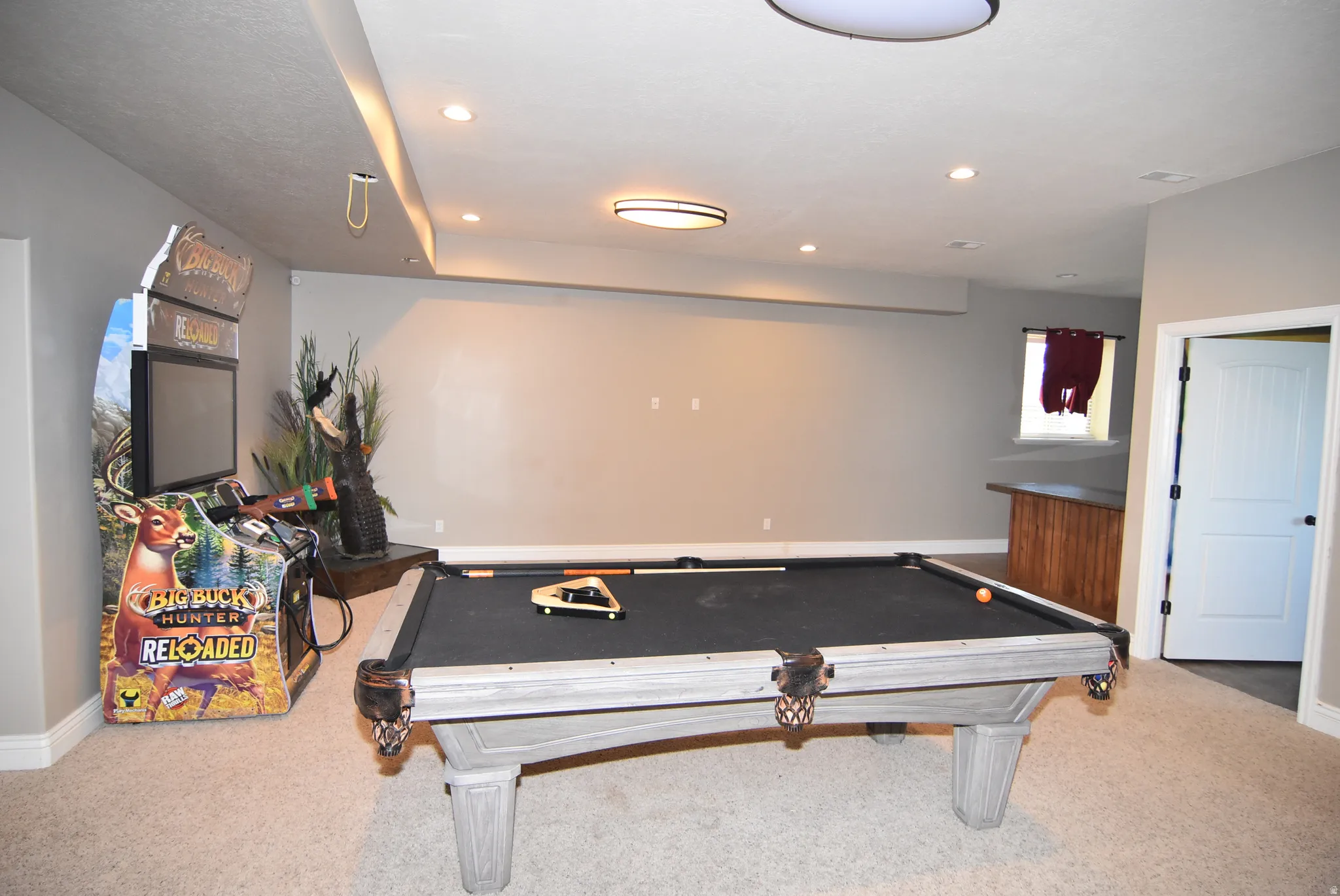 Spacious recreational room featuring a billiards table, recessed lighting, carpet flooring, a built-in wood-finish bar, and a white paneled door