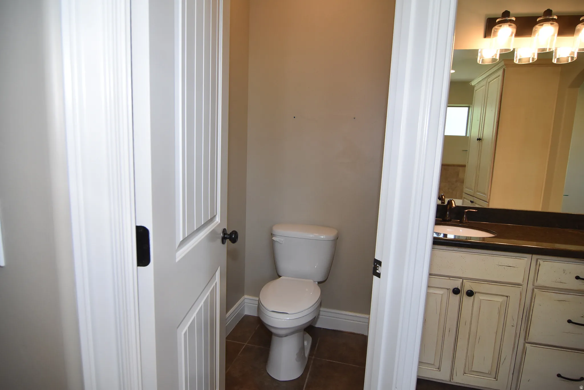 Owner's Powder room featuring a white toilet, tile flooring, and a beadboard door