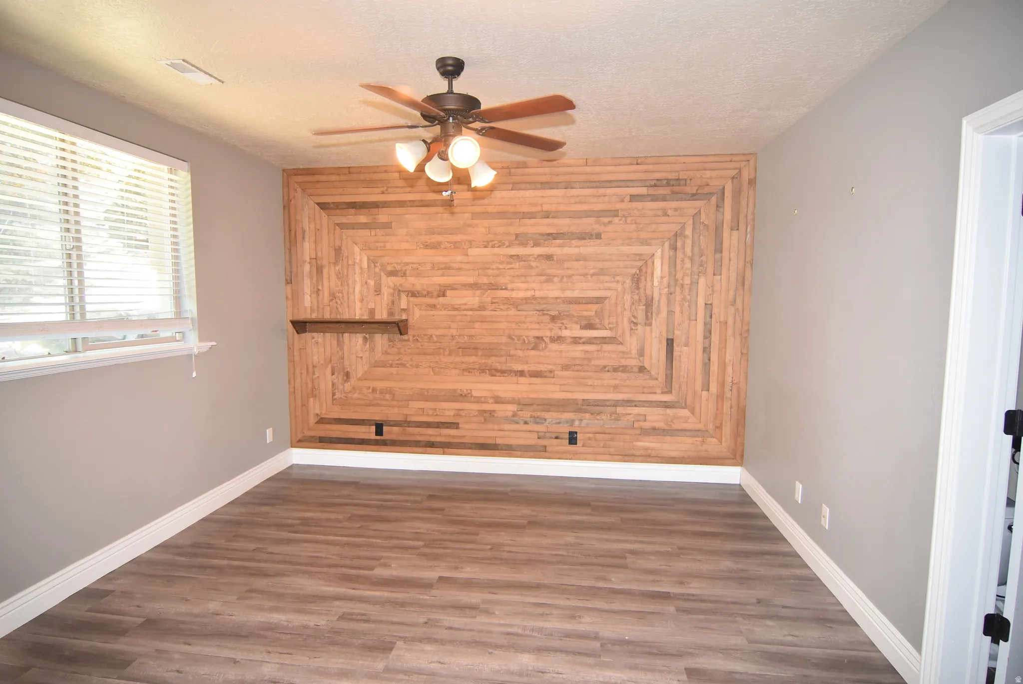 Accent wall featuring a geometric wood-finish pattern and an integrated floating shelf
