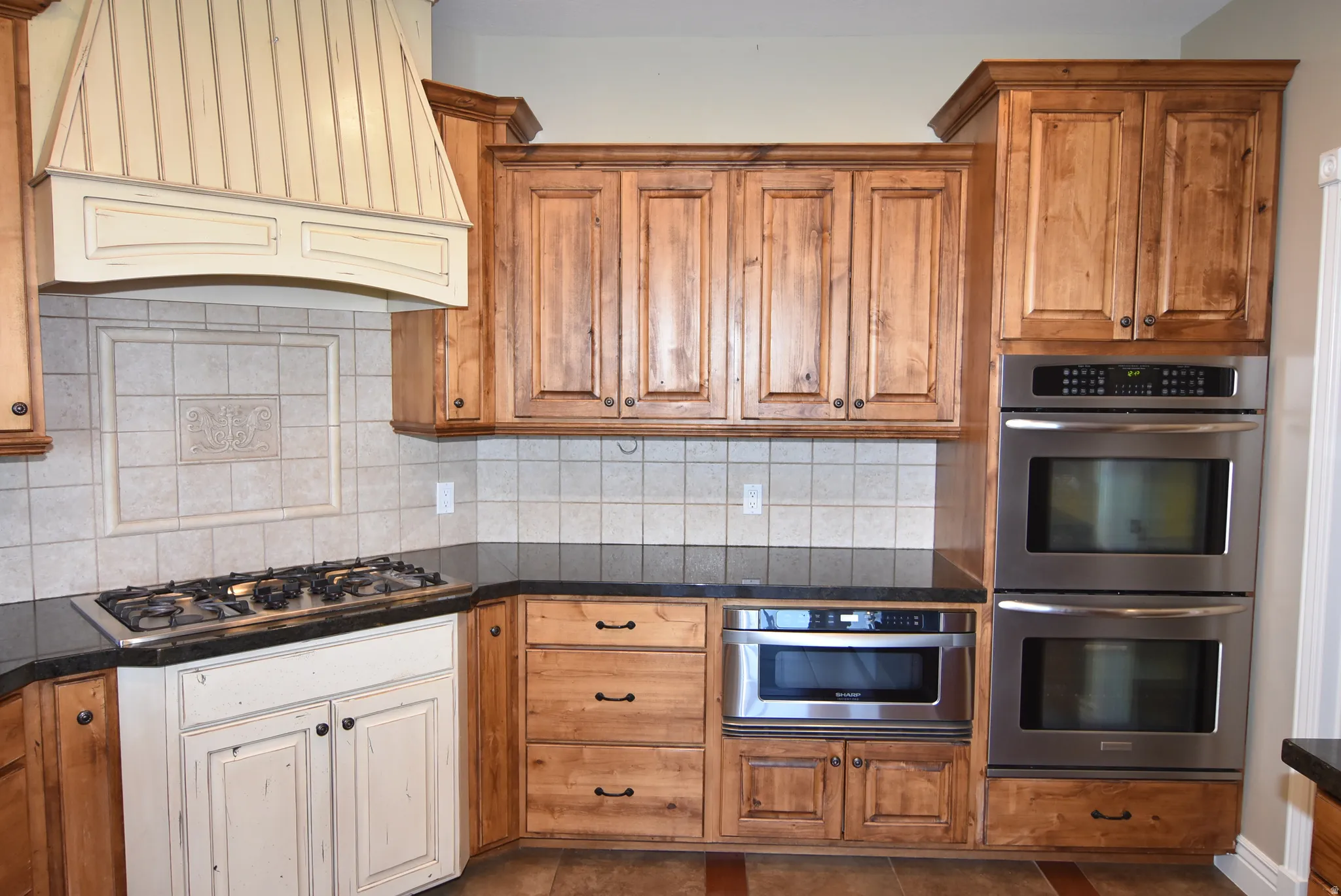 Kitchen featuring stainless steel double ovens, a built-in microwave, a gas cooktop, and dark countertops