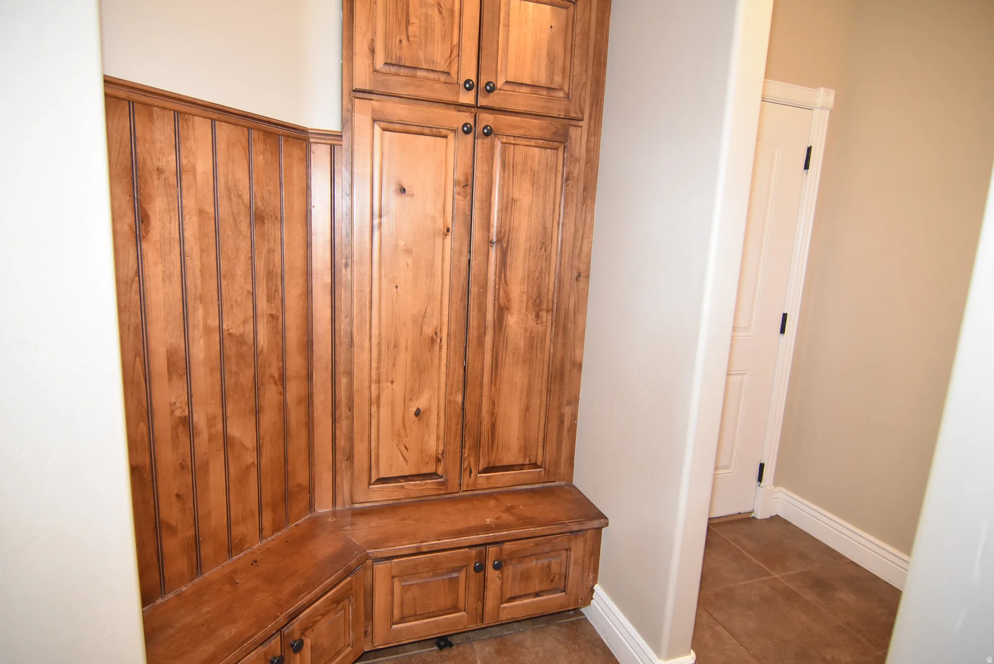 Built-in wood cabinetry with dark hardware, integrated bench seating, and wood-paneled wall accent