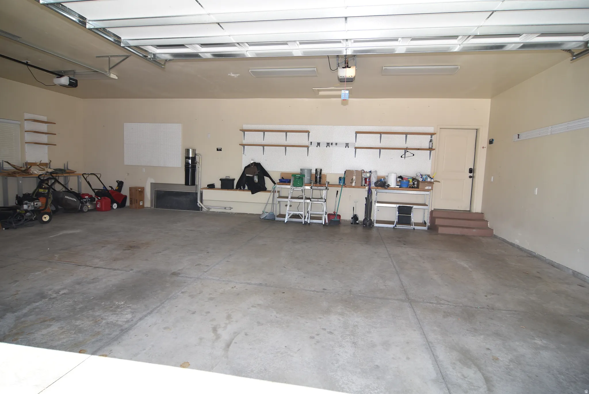 Spacious garage featuring concrete flooring, overhead lighting, and an automatic garage door opener