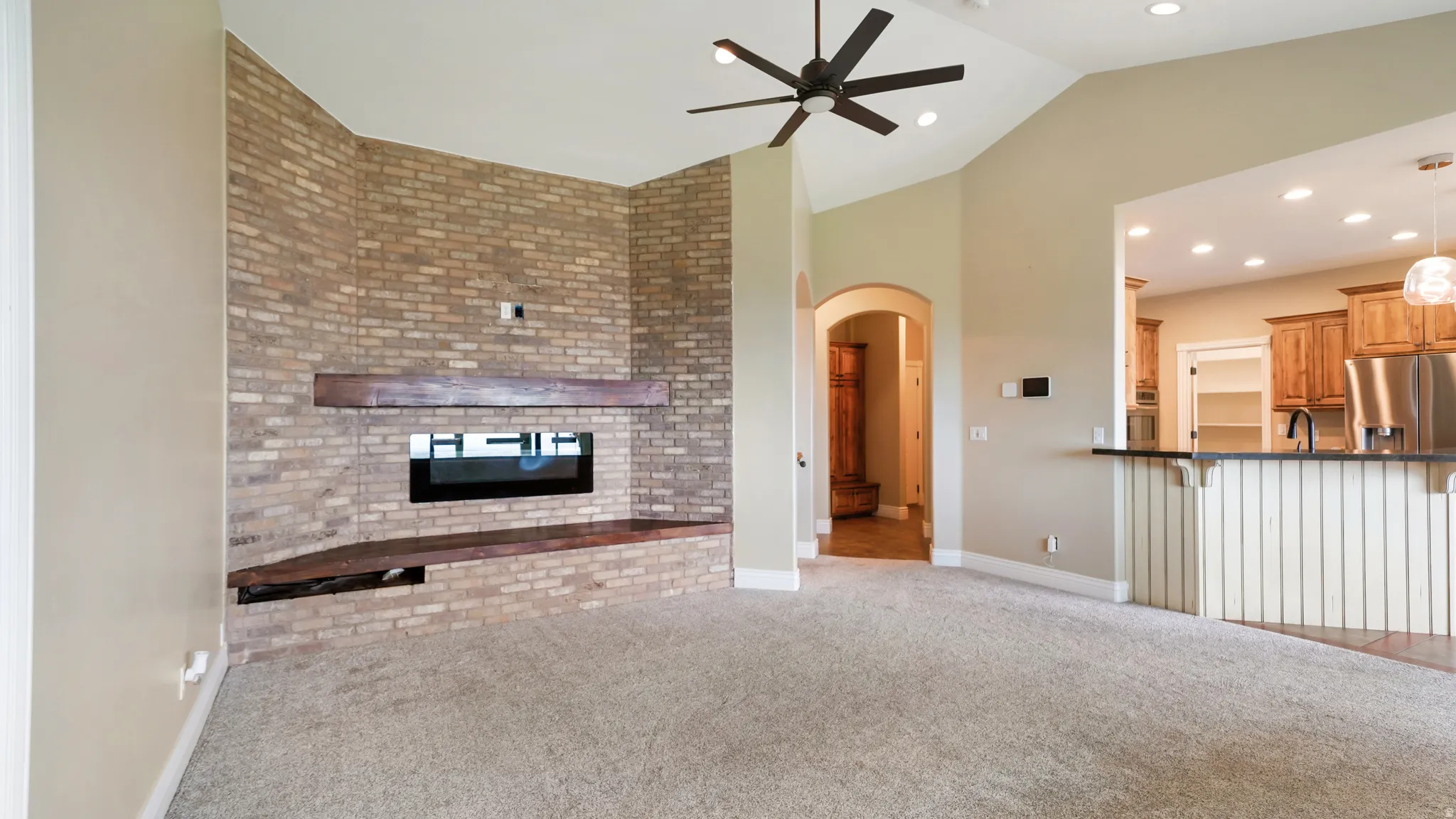 Brick accent wall featuring a modern fireplace with a dark wood mantel and hearth