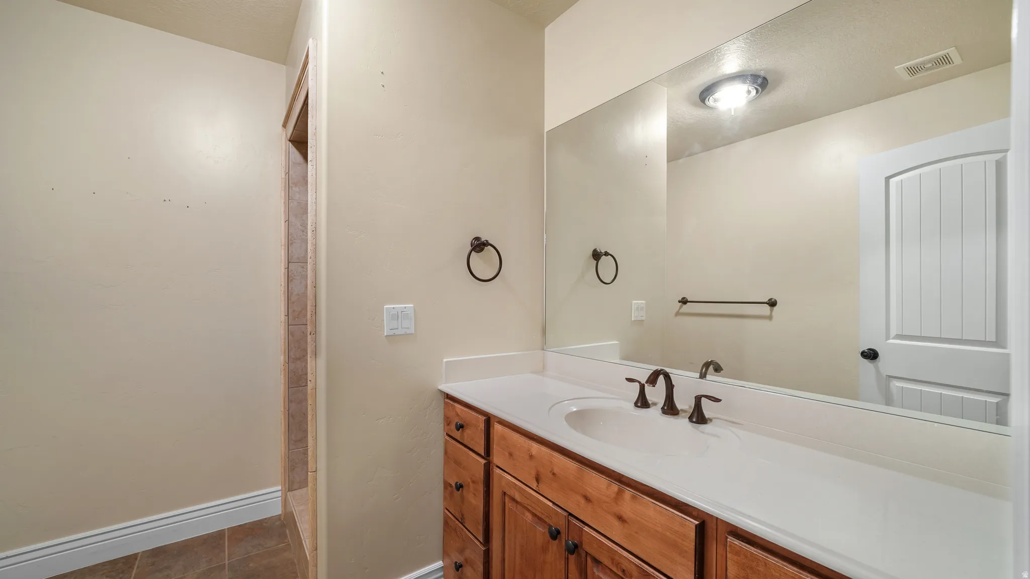 Bathroom vanity featuring a single basin, light-toned countertop, and wood-finish cabinetry