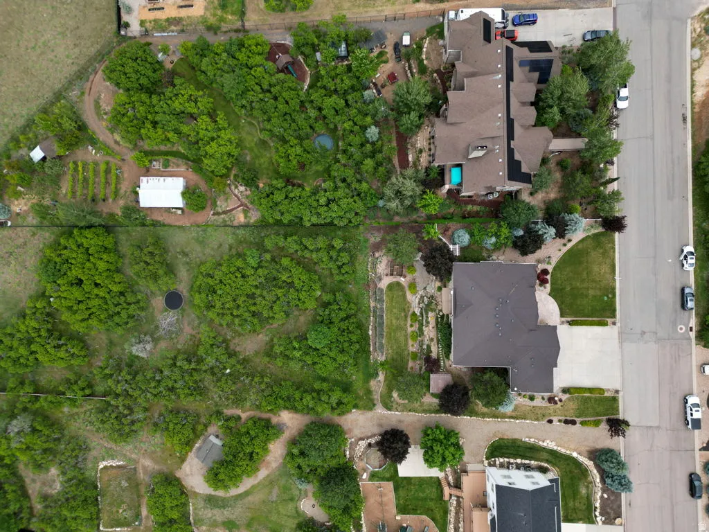 Expansive property featuring dense tree coverage, a dedicated garden area, and a large residential structure with a dark-toned roof