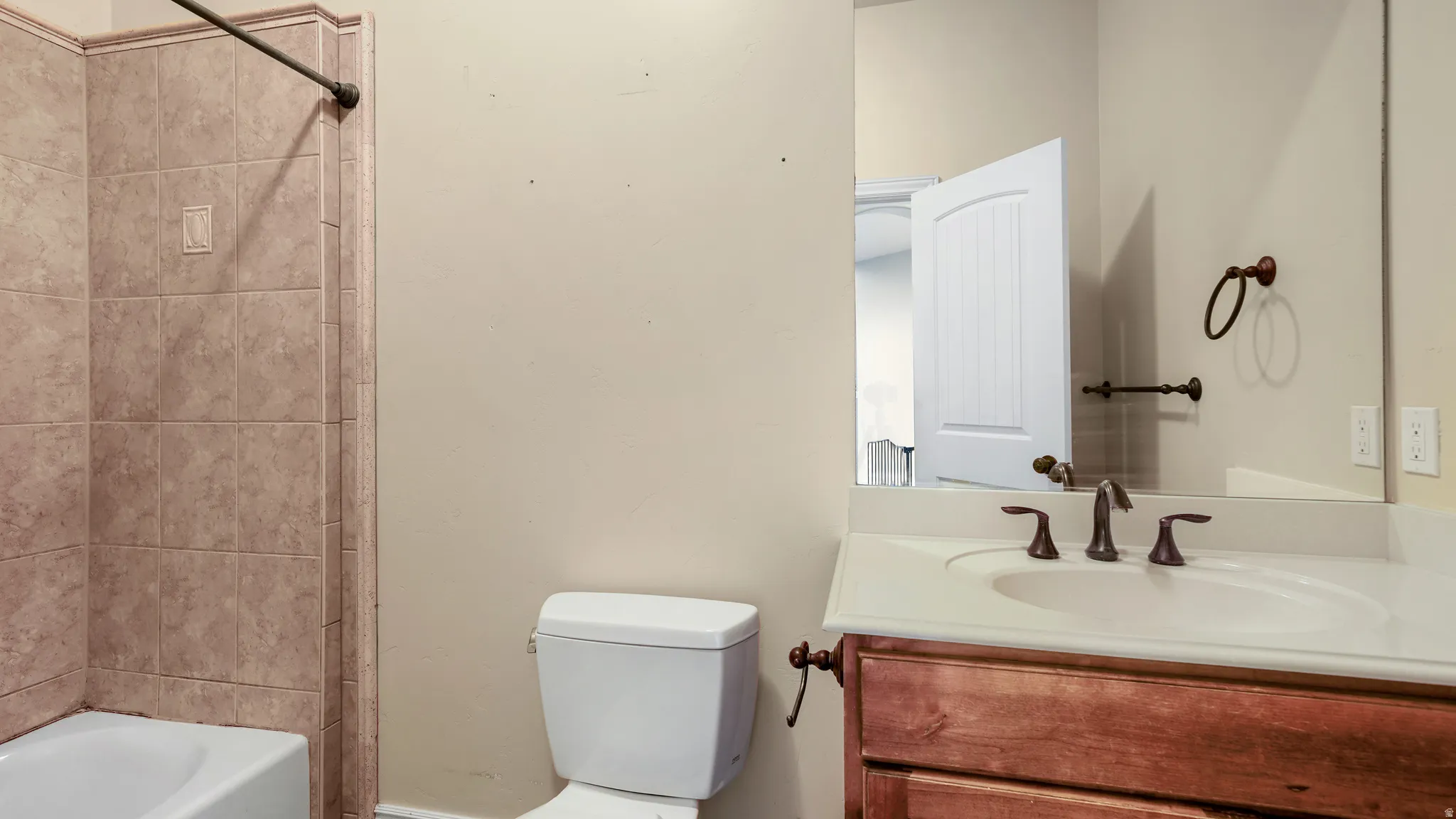 Bathroom vanity with a light-colored countertop, integrated sink, and bronze-finish faucet