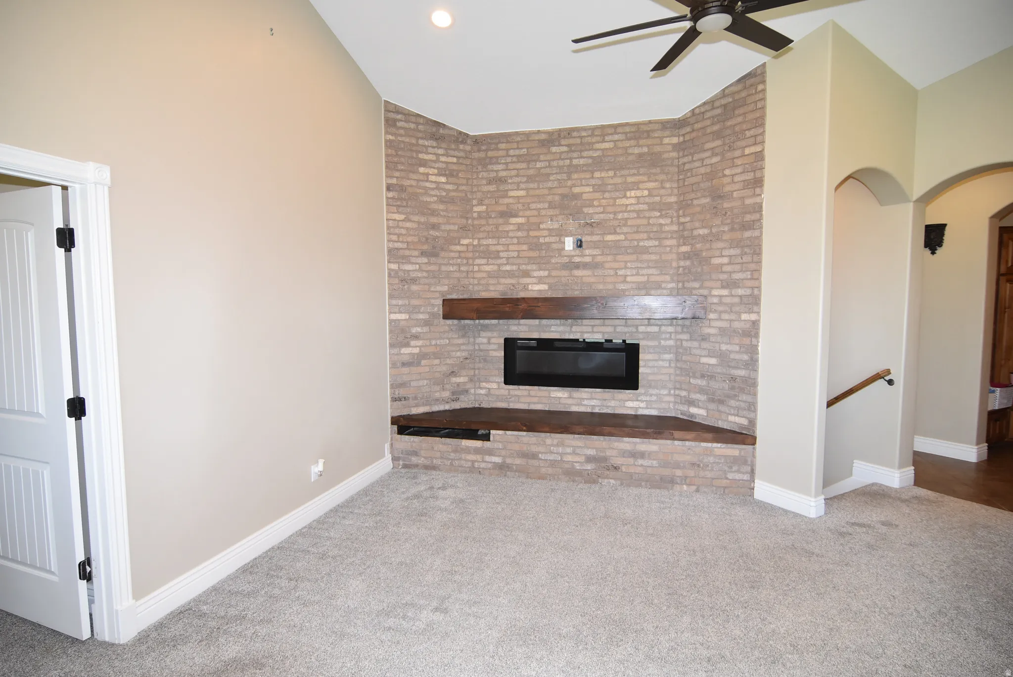 Living space featuring a corner brick fireplace with a wood mantel and hearth