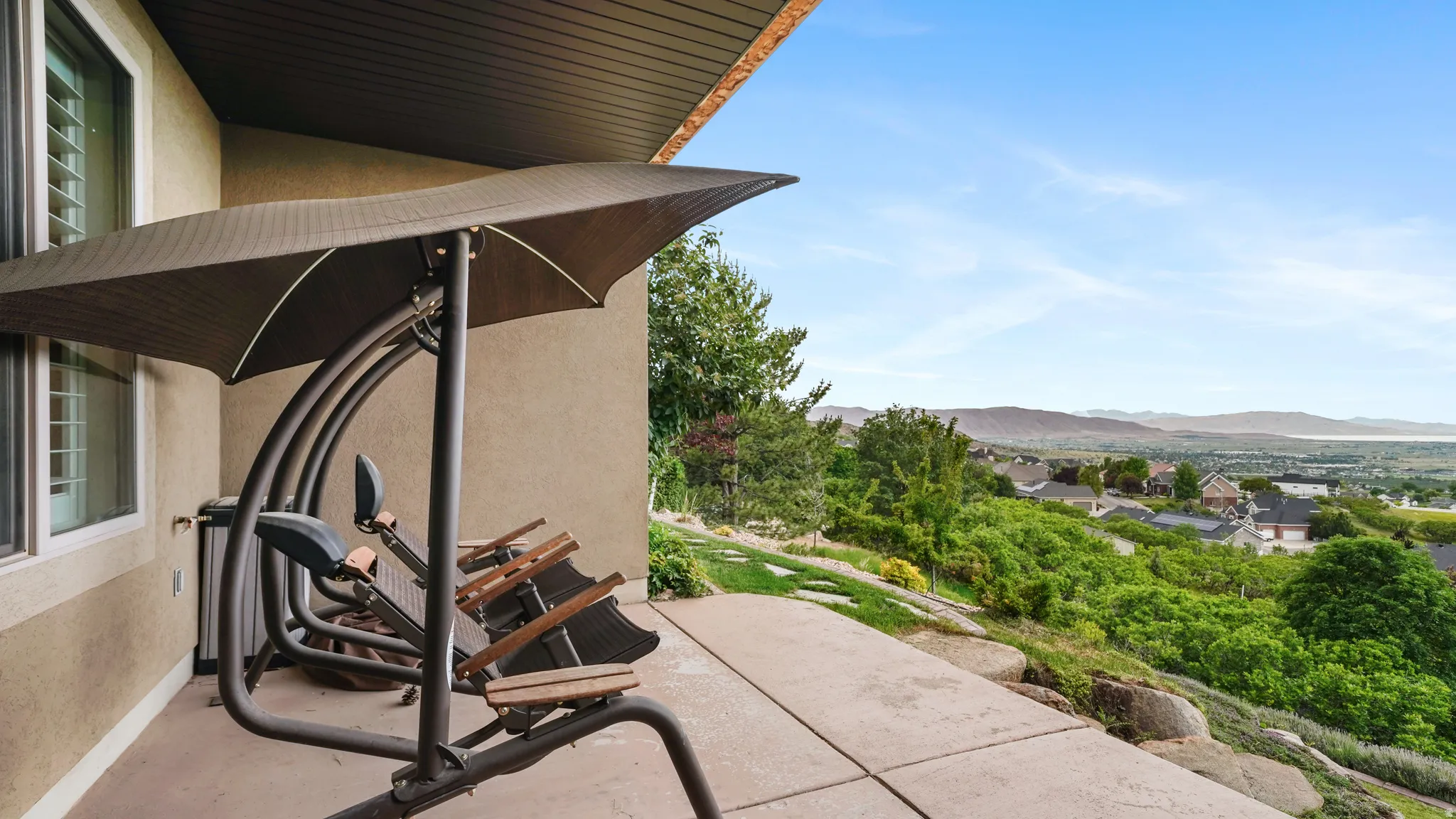 Outdoor patio featuring a concrete surface, surrounding natural rock formations, and abundant green foliage