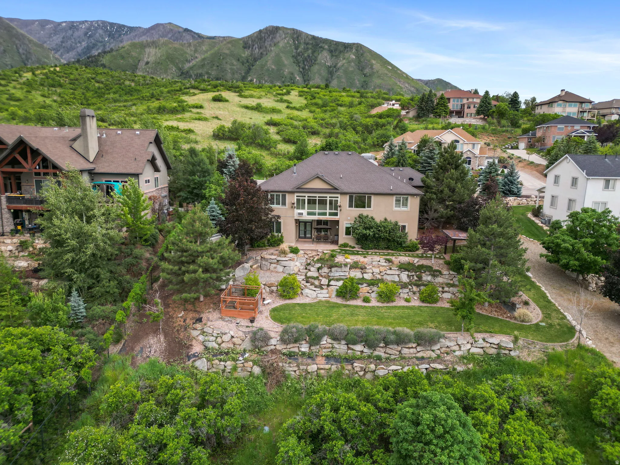 Spacious residence featuring a multi-level terraced backyard with manicured lawns and stone retaining walls