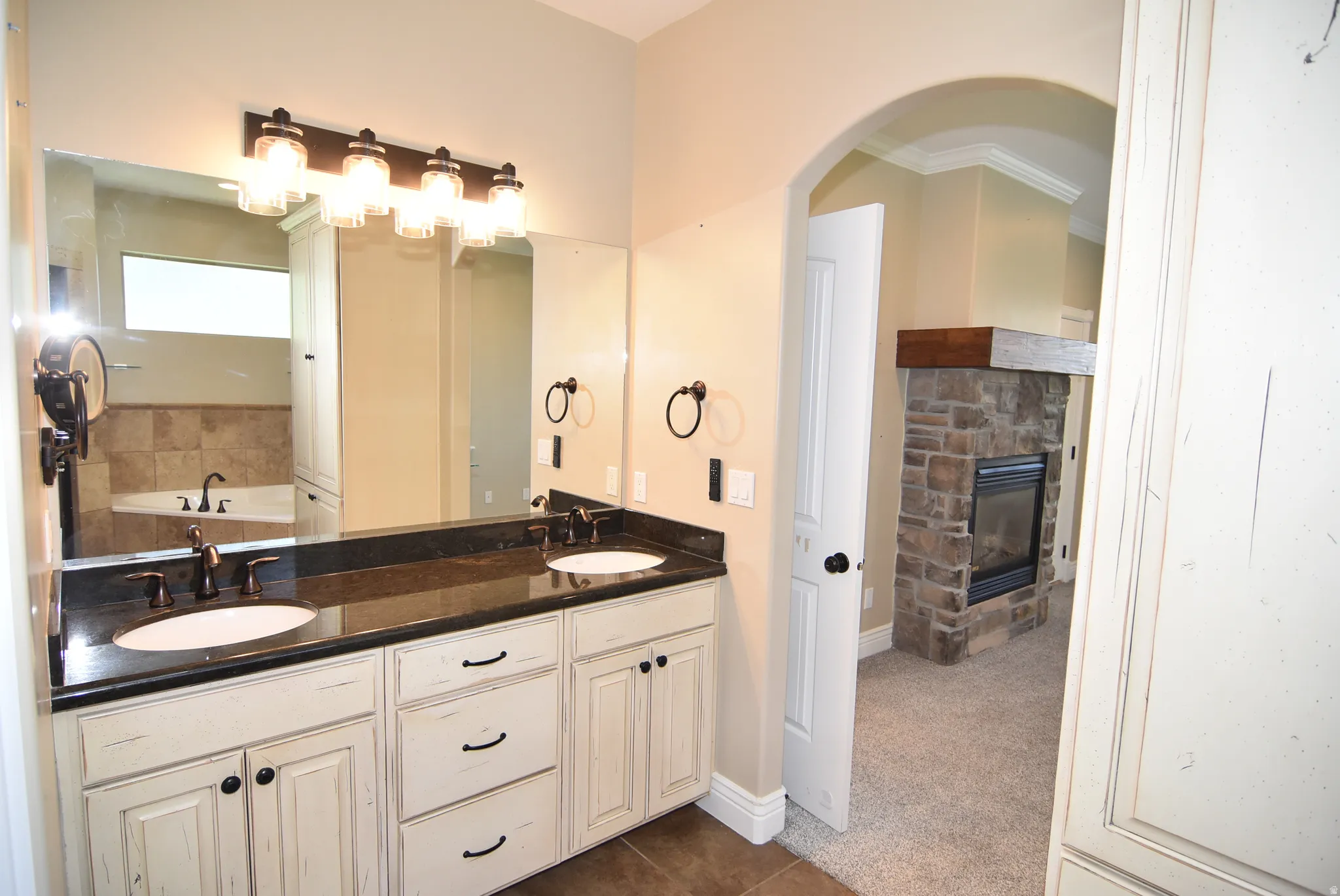 Owner's Double vanity with dark countertops and distressed white cabinetry